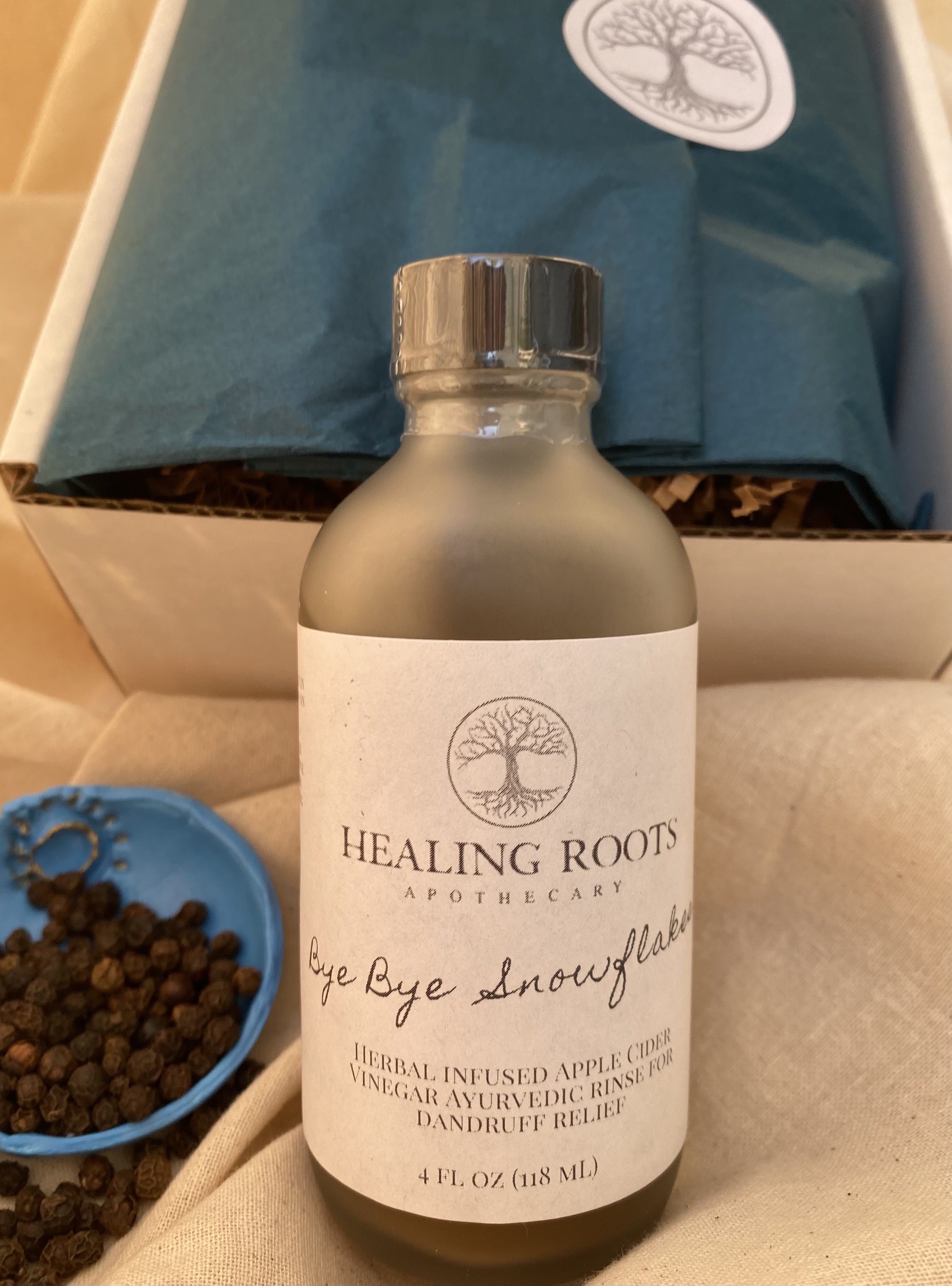 Rinses are carefully packaged in a flip top box. Lining the interior of the box is peacock blue wrapping paper adorned with a circular sticker with the tree of life logo printed on it.