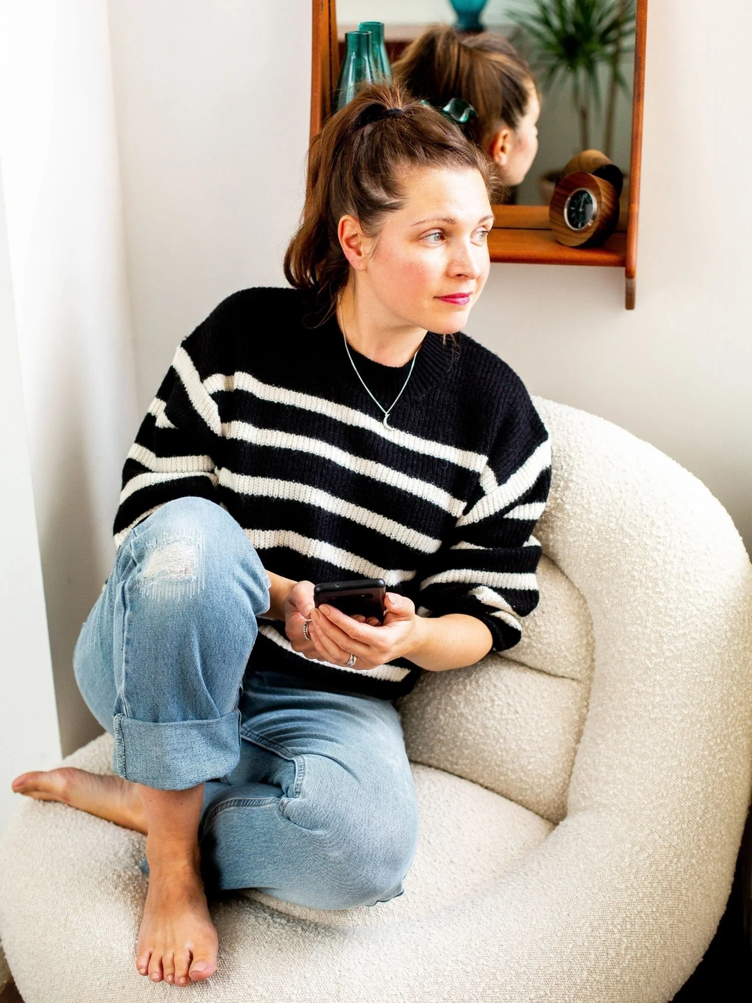 Sam Ferguson, course creator of Found & Followed wearing stripy jumper and gazing off to the side, holding a phone