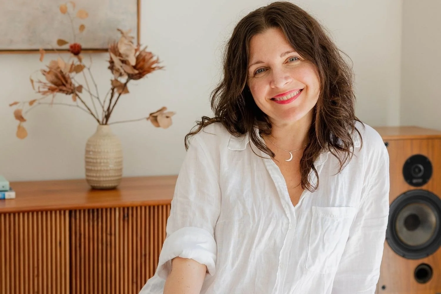 darh haired woman dressed in white linen shirt and smiling at the camera