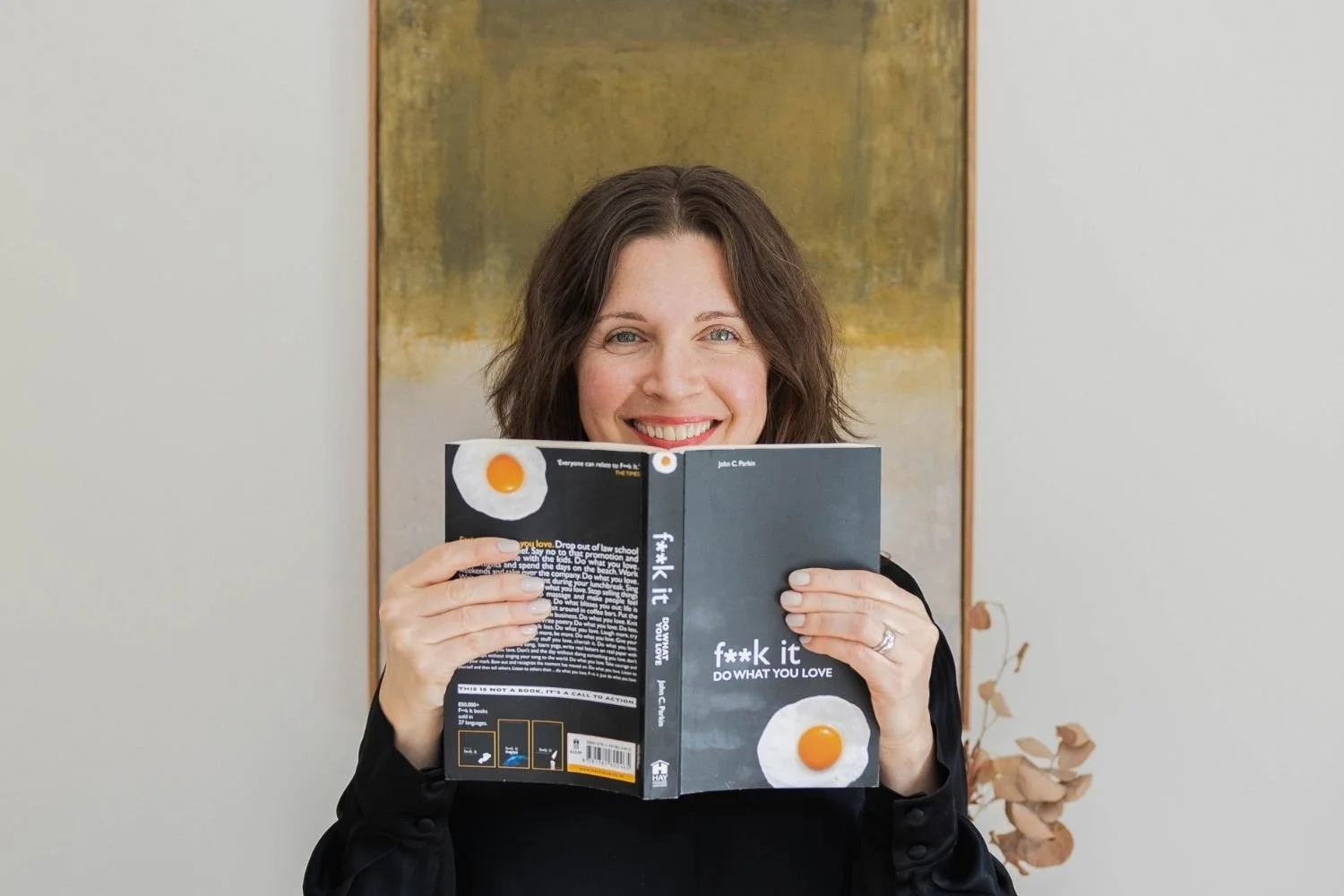 woman peeking over the top of a book and smiling