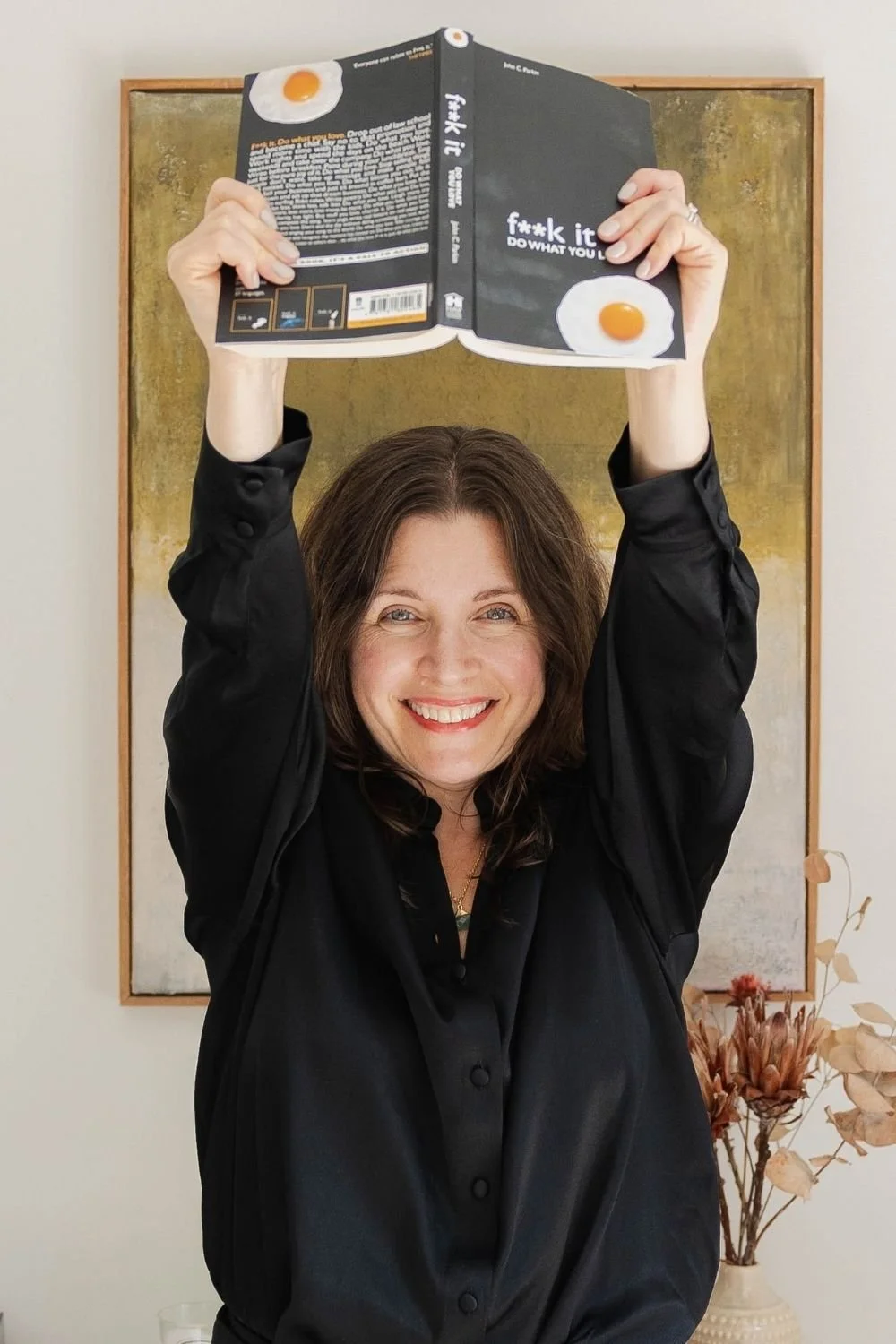 woman holding book above her head and smiling