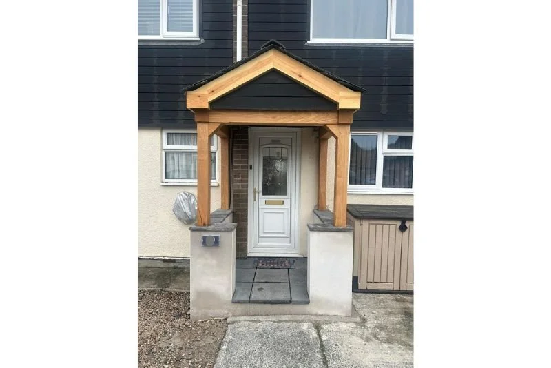 A room under construction with unfinished walls, a sloped ceiling with a skylight, three windows, and a tiled floor with footprints. Tools and materials are on the windowsill.