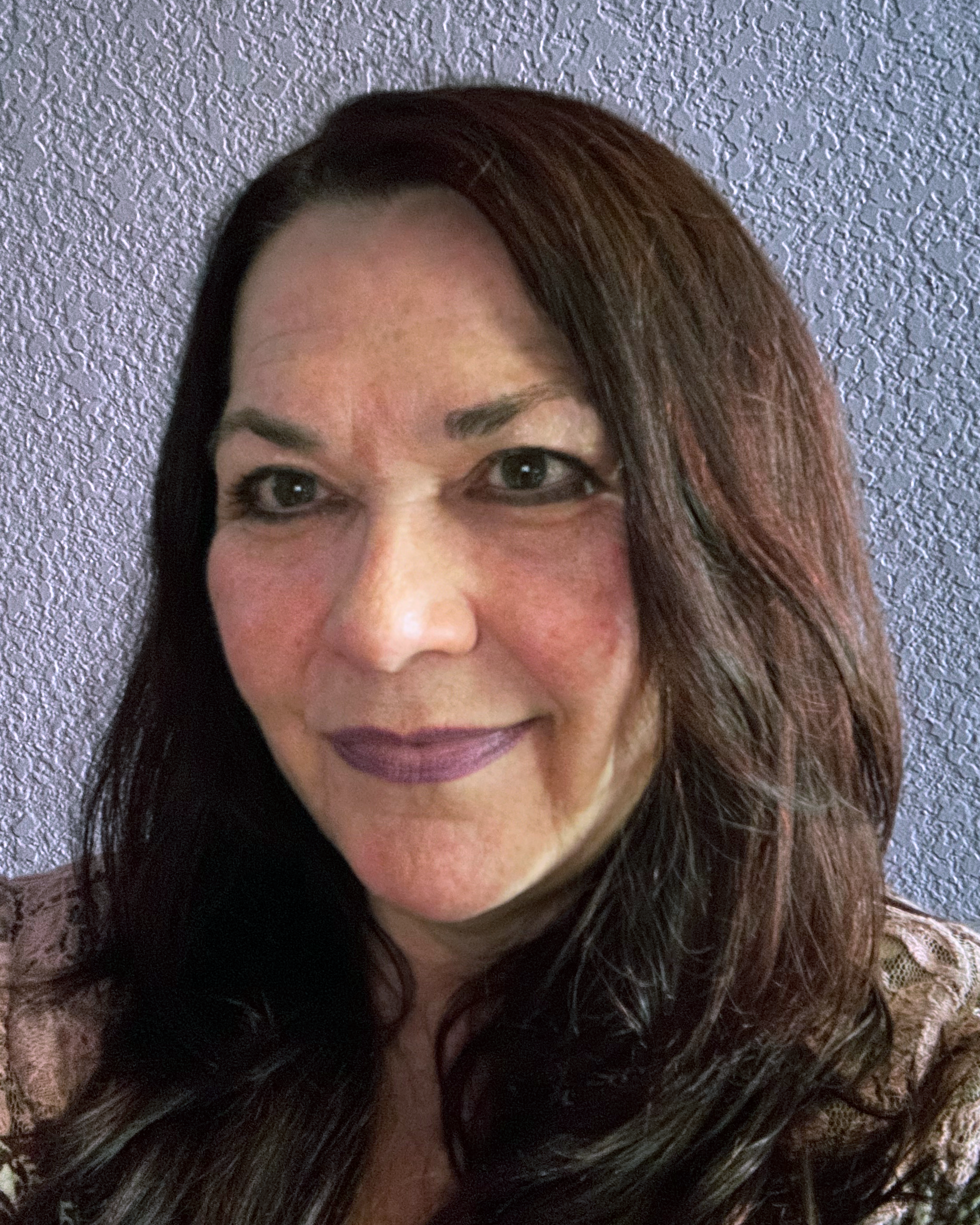Picture of Dr. Viktoria Walda light skinned femme with long dark straight hair smiling wearing a black blouse and chunky orange and brown necklace