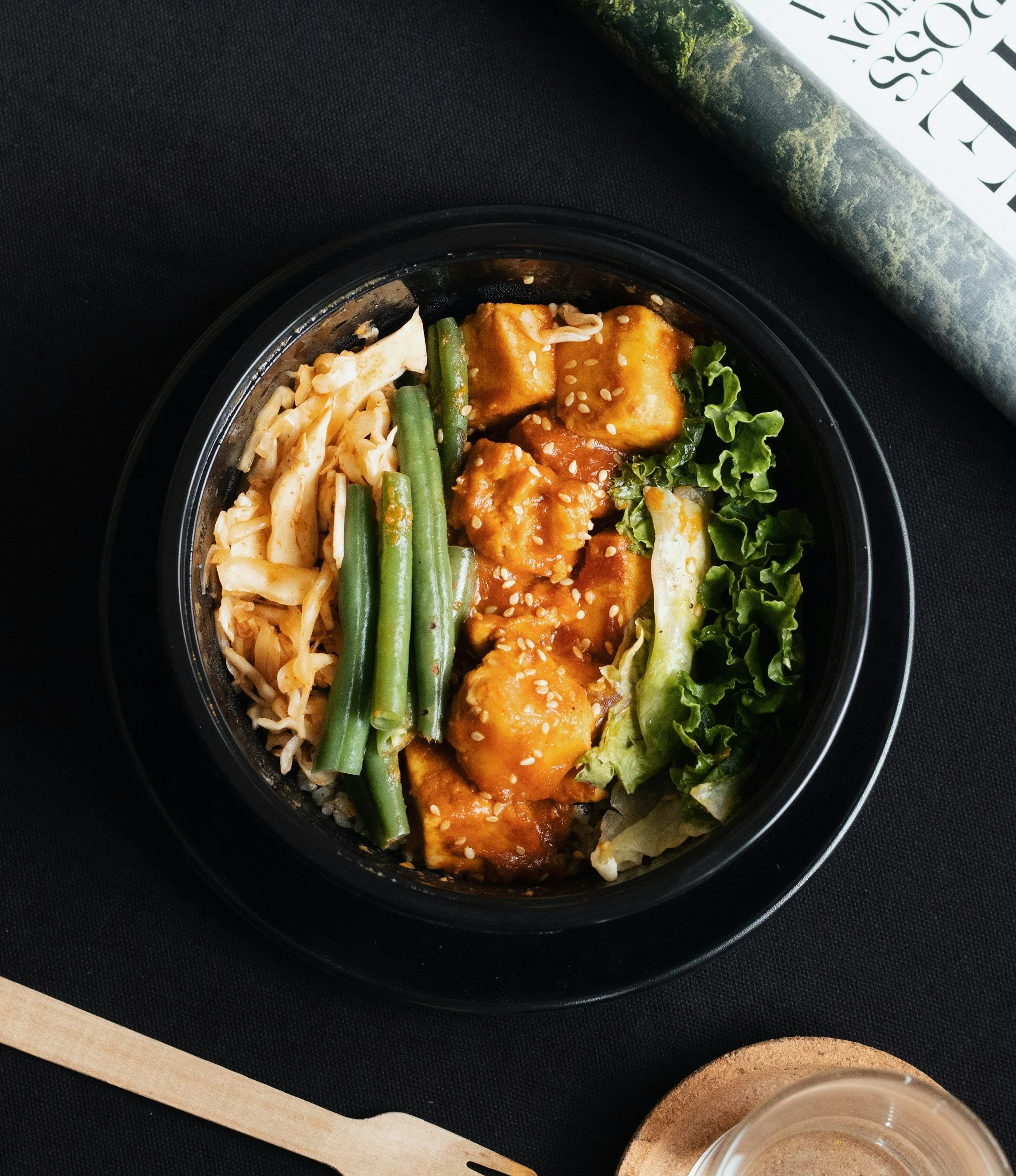 Black bowl of tofu, green beans and noodles
