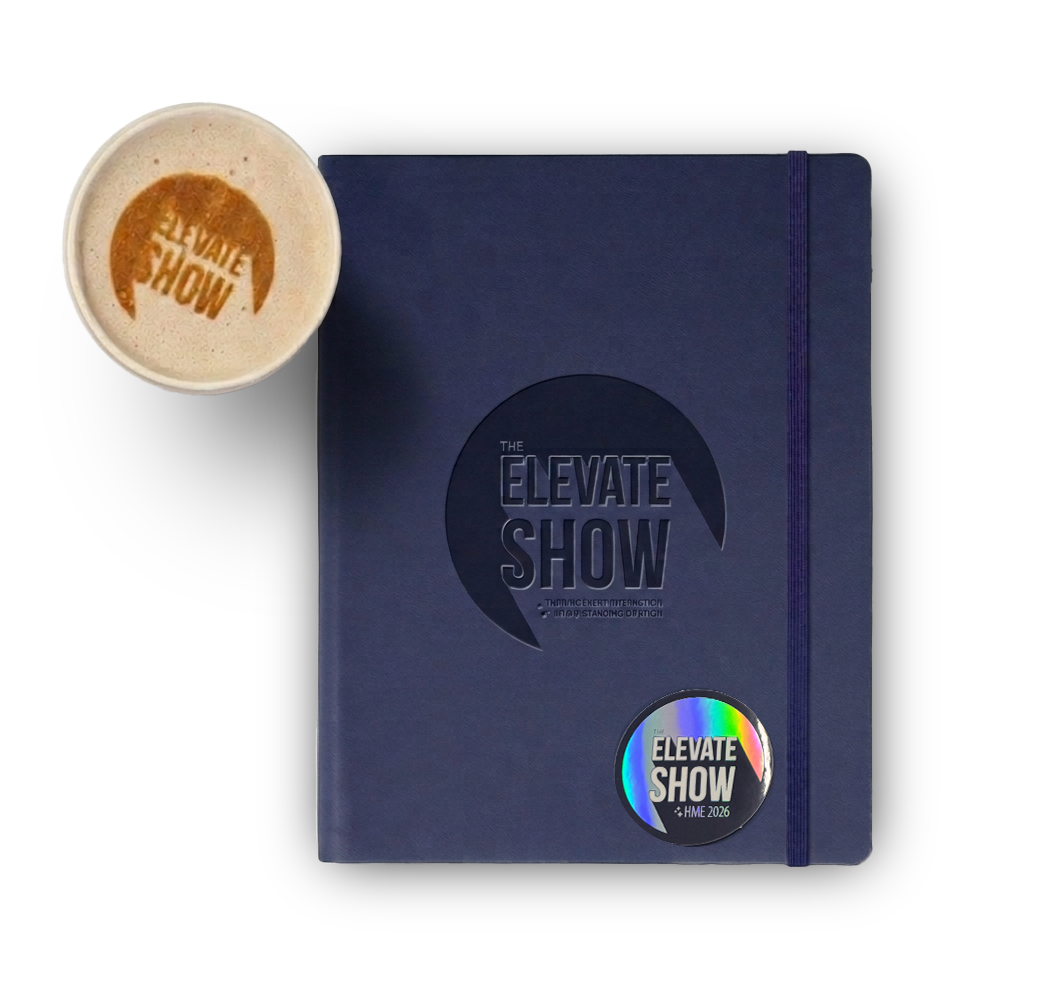 A blue hardcover notebook with a black elastic band and a holographic sticker, placed next to a cup of coffee with foam and a logo on top, on a black background.