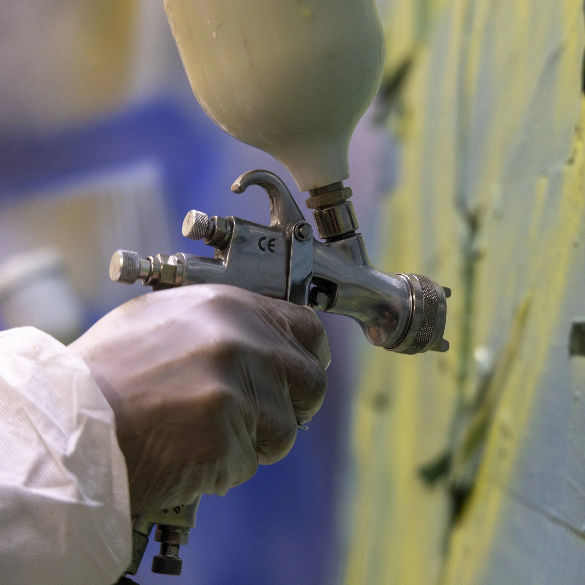 A worker using a spray gun in a paint workshop
