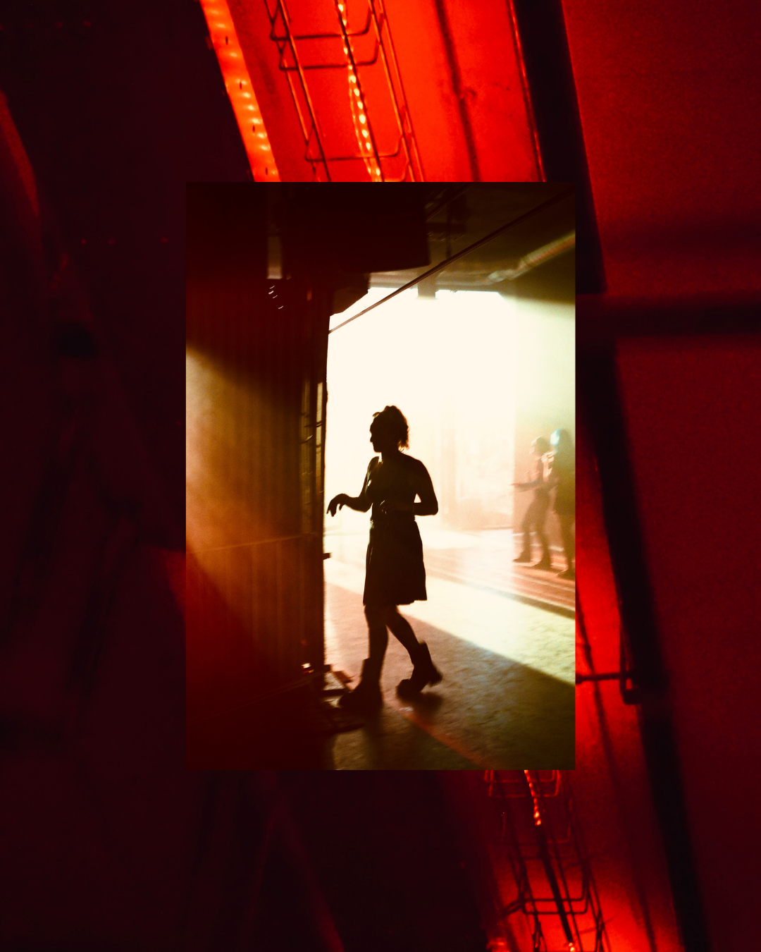 Silhouette of a woman walking through a doorway with sunlight backlighting the scene, and people in the background.