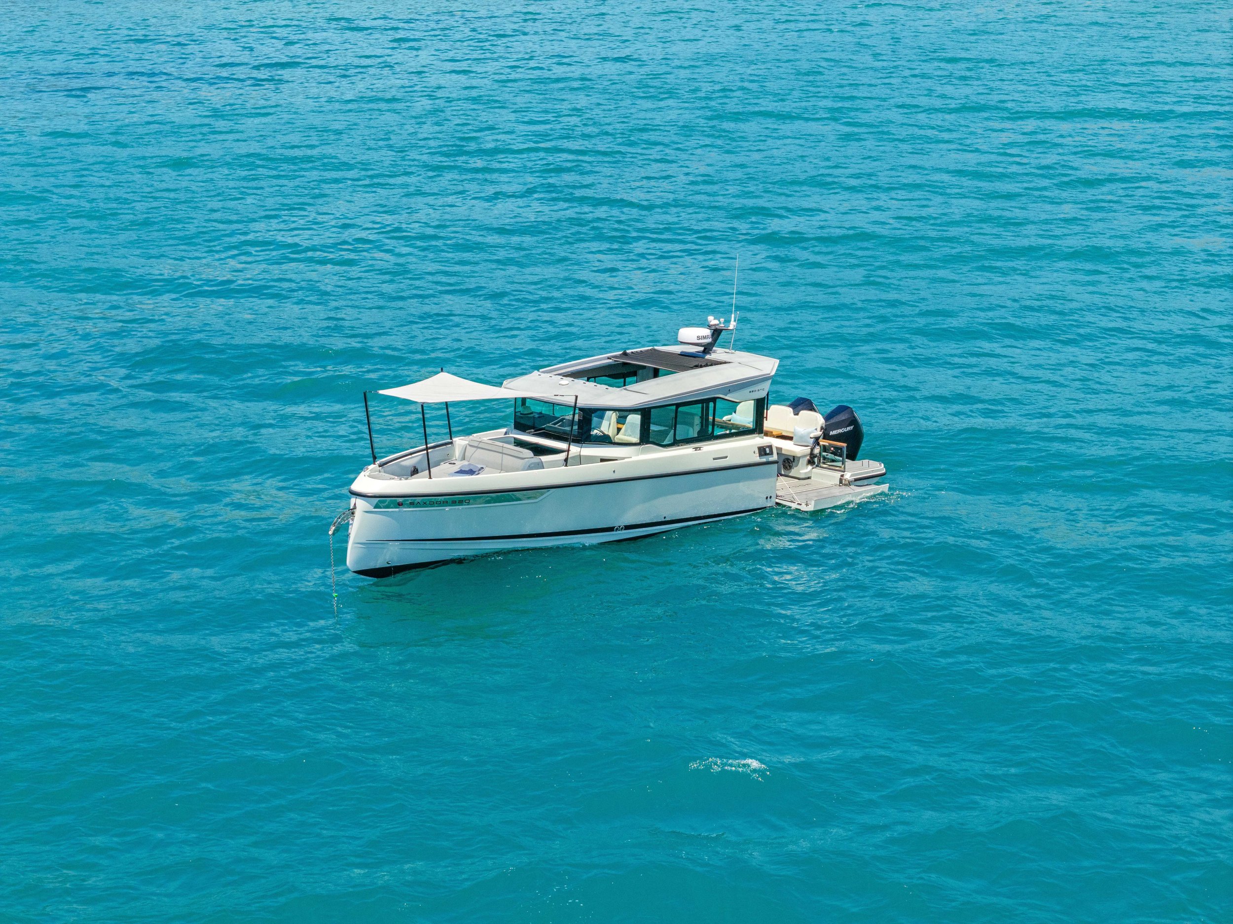 A white motorboat floating on calm, turquoise water under a clear sky.