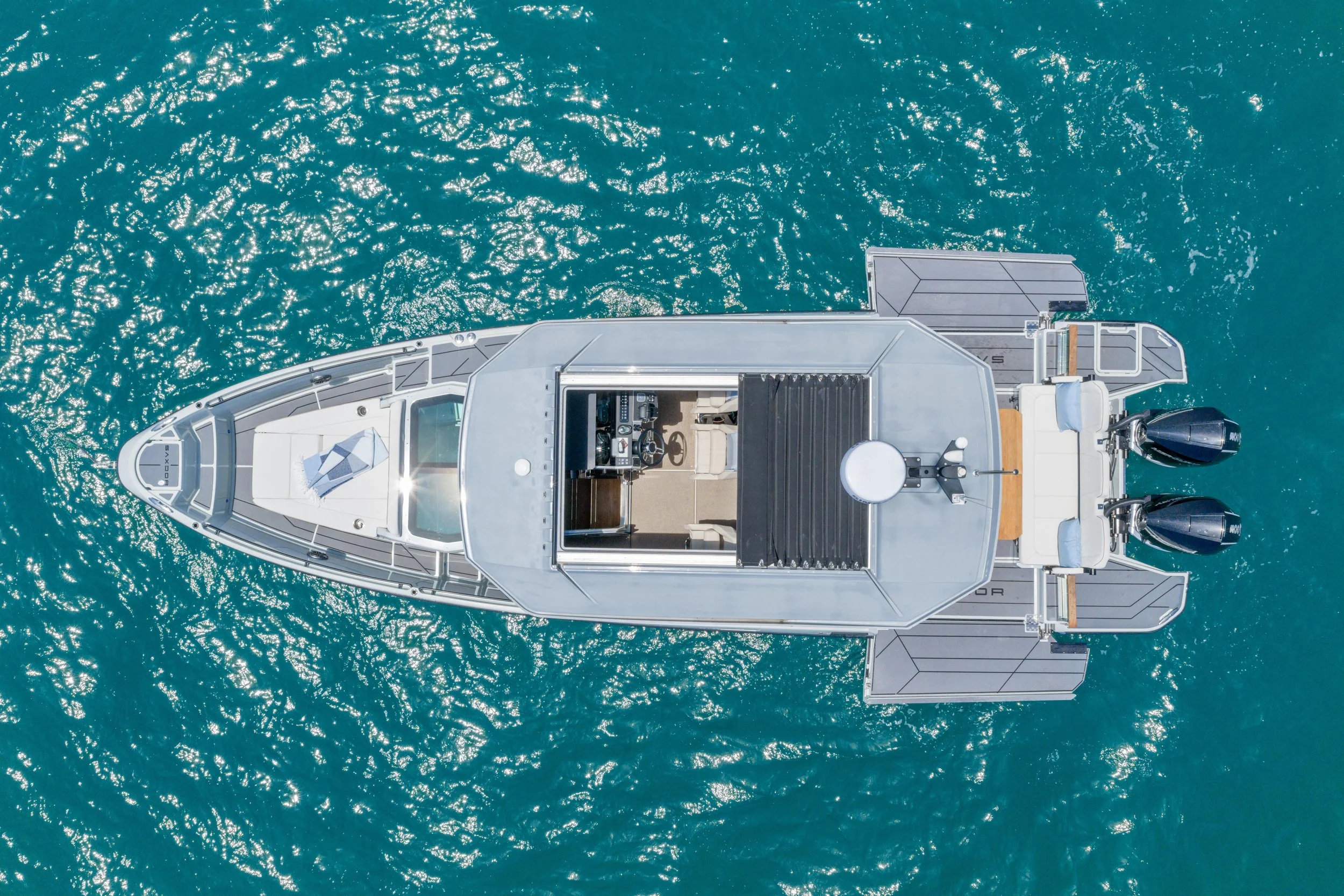 Aerial view of a white yacht on turquoise water with sunlight reflections.