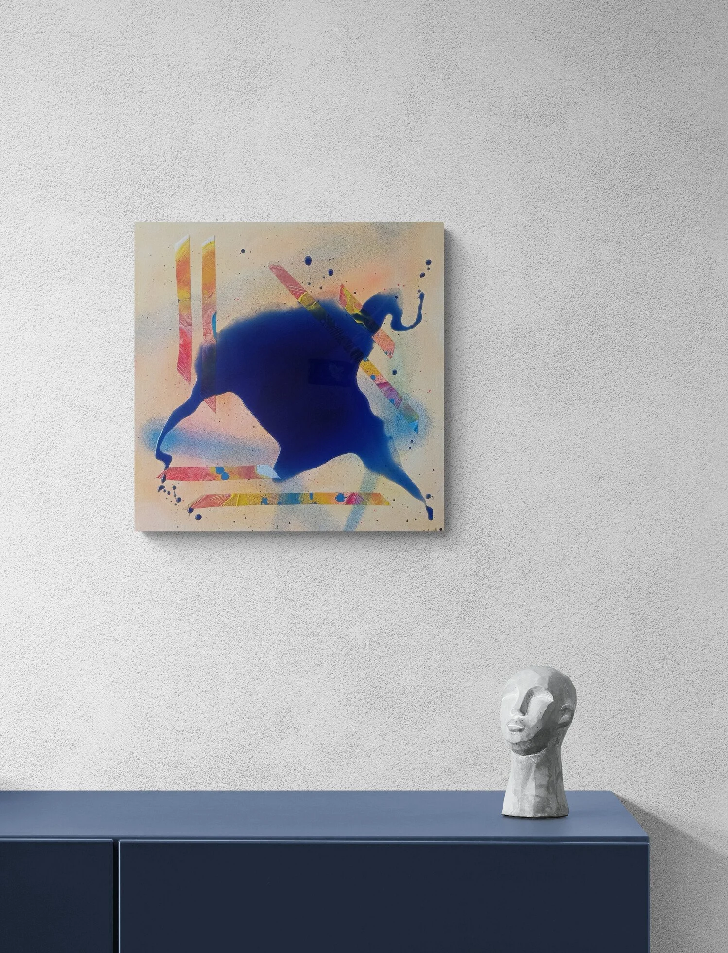 Wall art of a blue and pink abstract animal figure hanging on a white wall and a modern white sculpture of a person's head and neck on a dark blue cabinet.