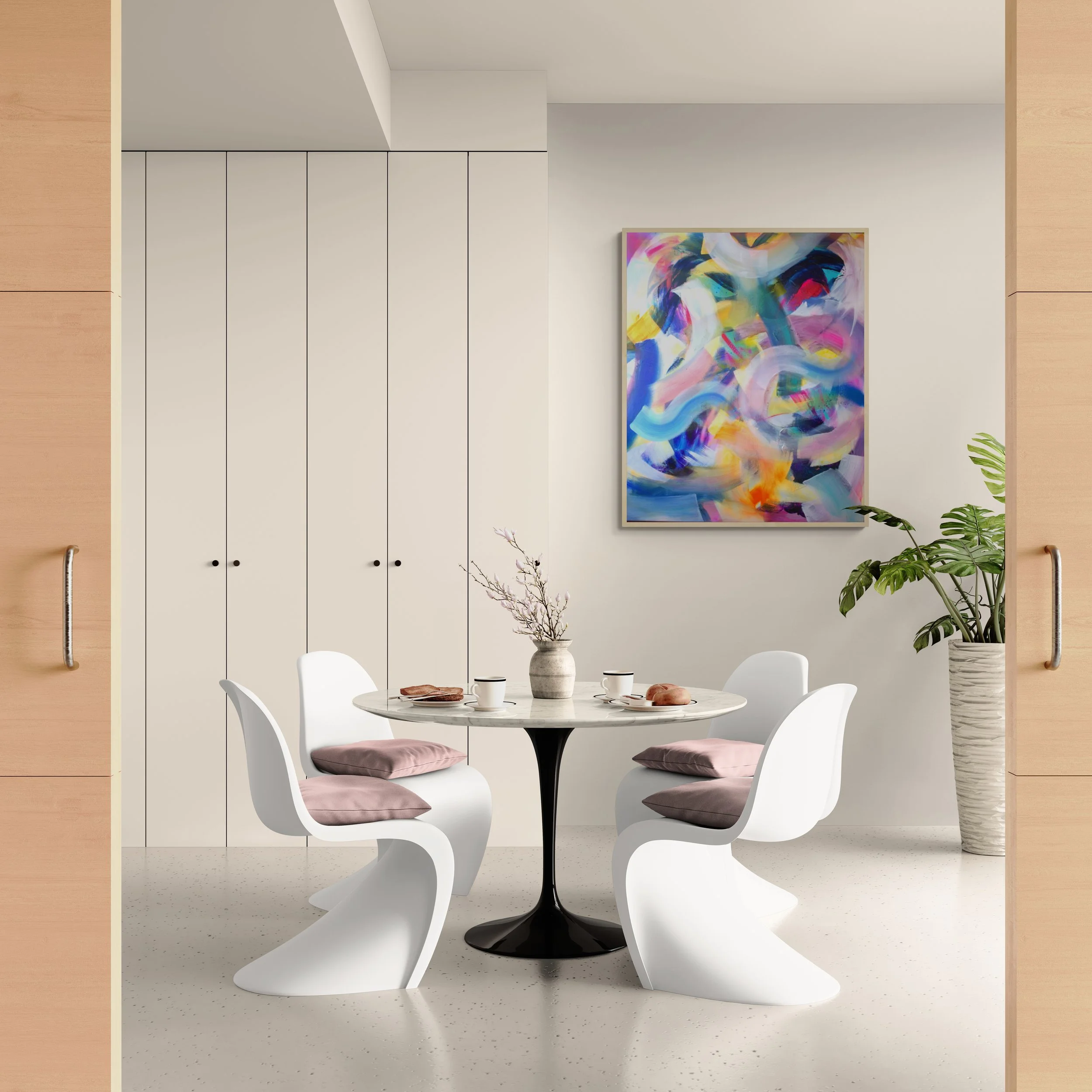A modern dining room with a round white table, four white chairs with pink cushions, a potted plant, and abstract colorful artwork on the wall.