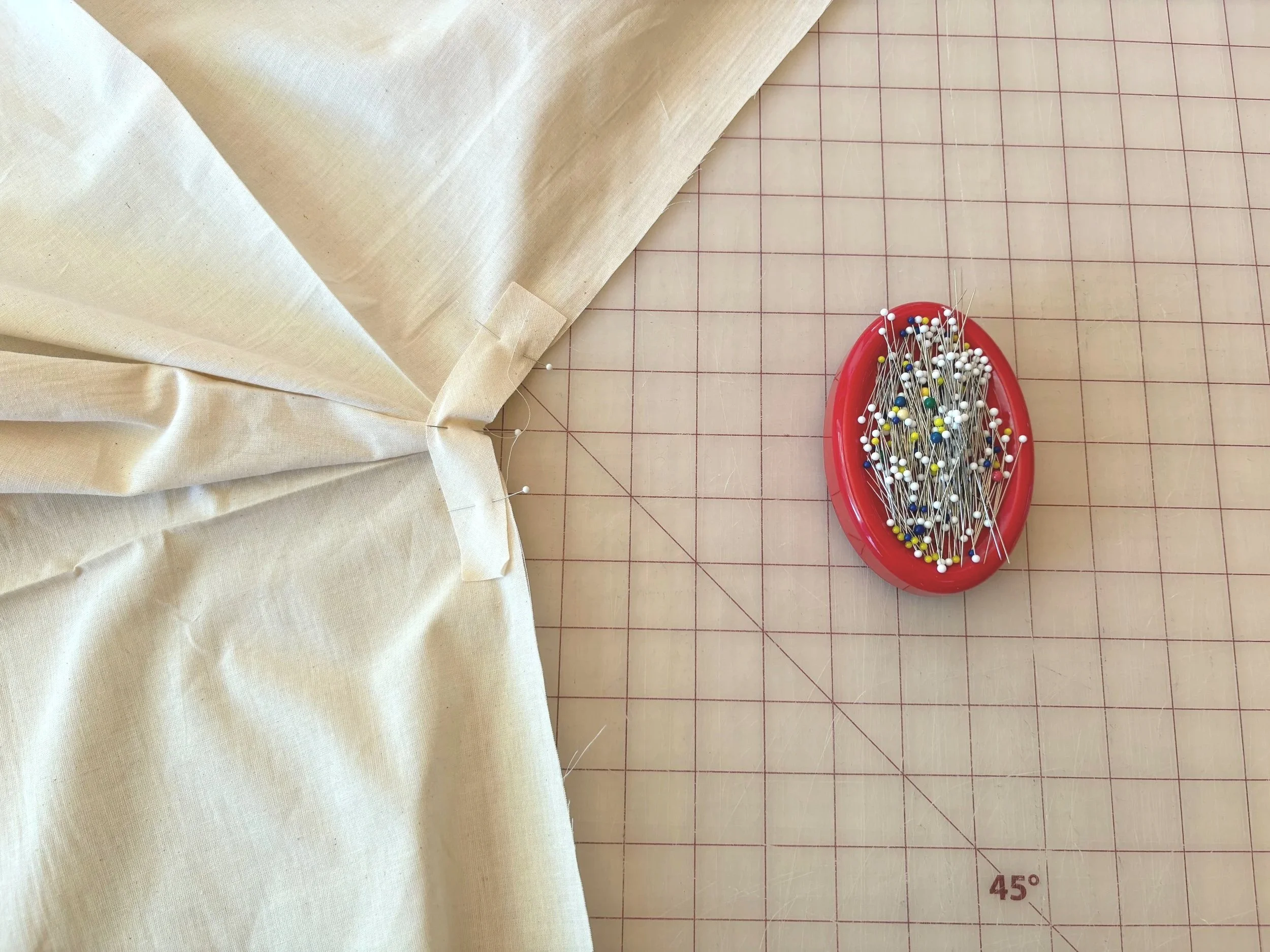 Close-up of bias strip pinned at the slit point, right sides together, with pins and a pincushion alongside