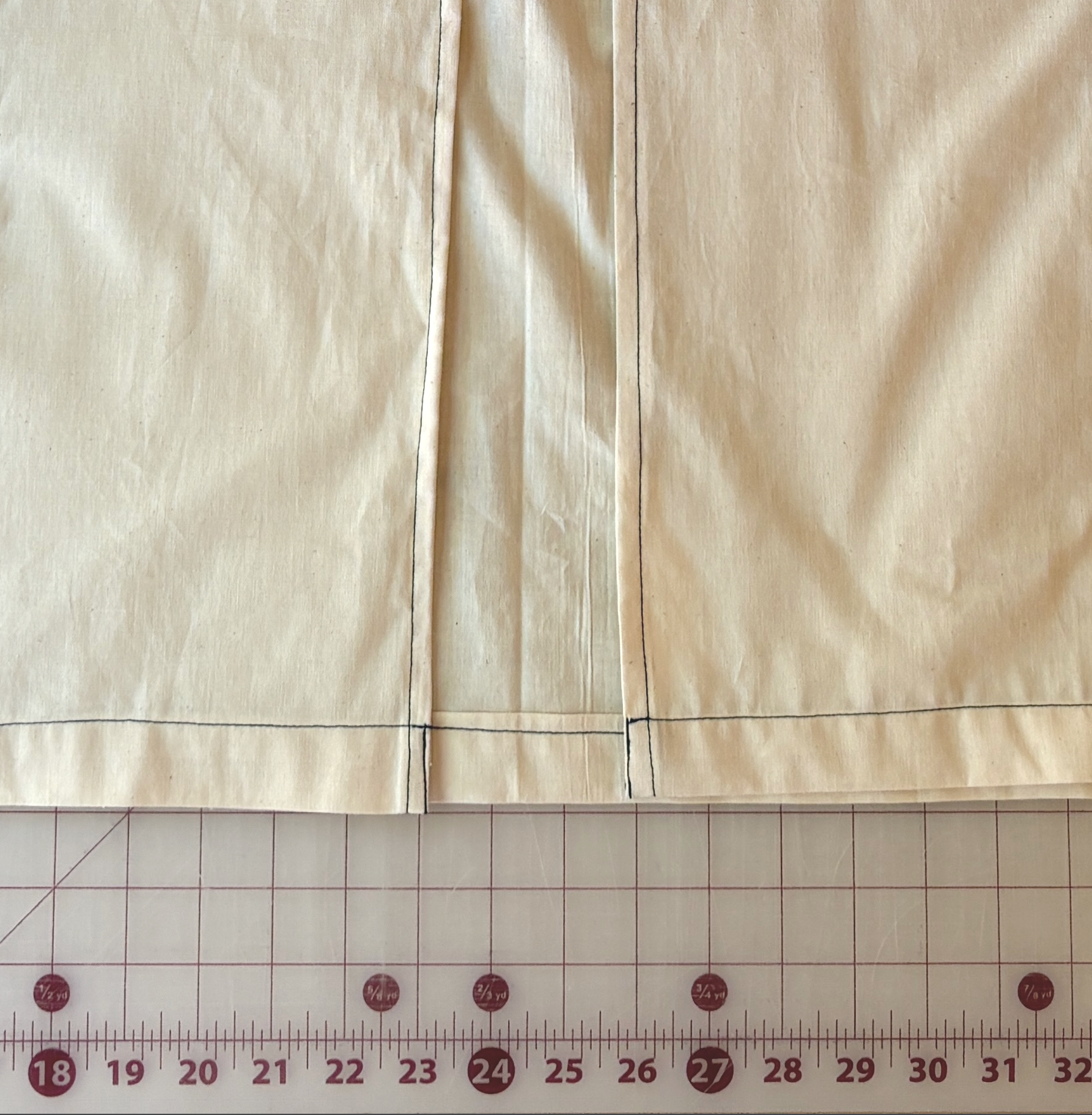 Bottom corner where the front opening's folded edge meets the finished hem, with topstitching visible along both seams
