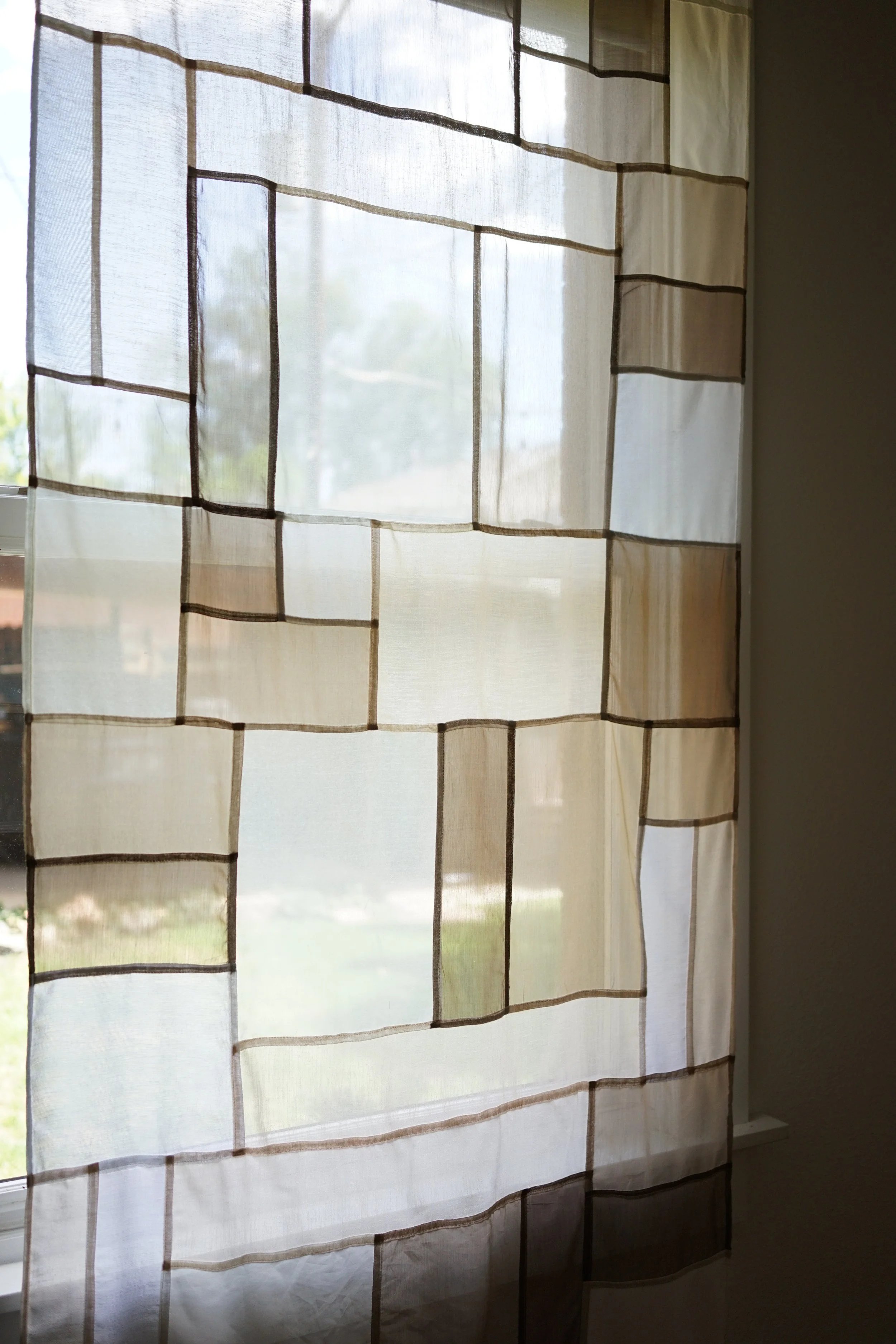 Neutral jogakbo patchwork curtain detail showing cream, beige, and taupe rectangles with dark seam binding