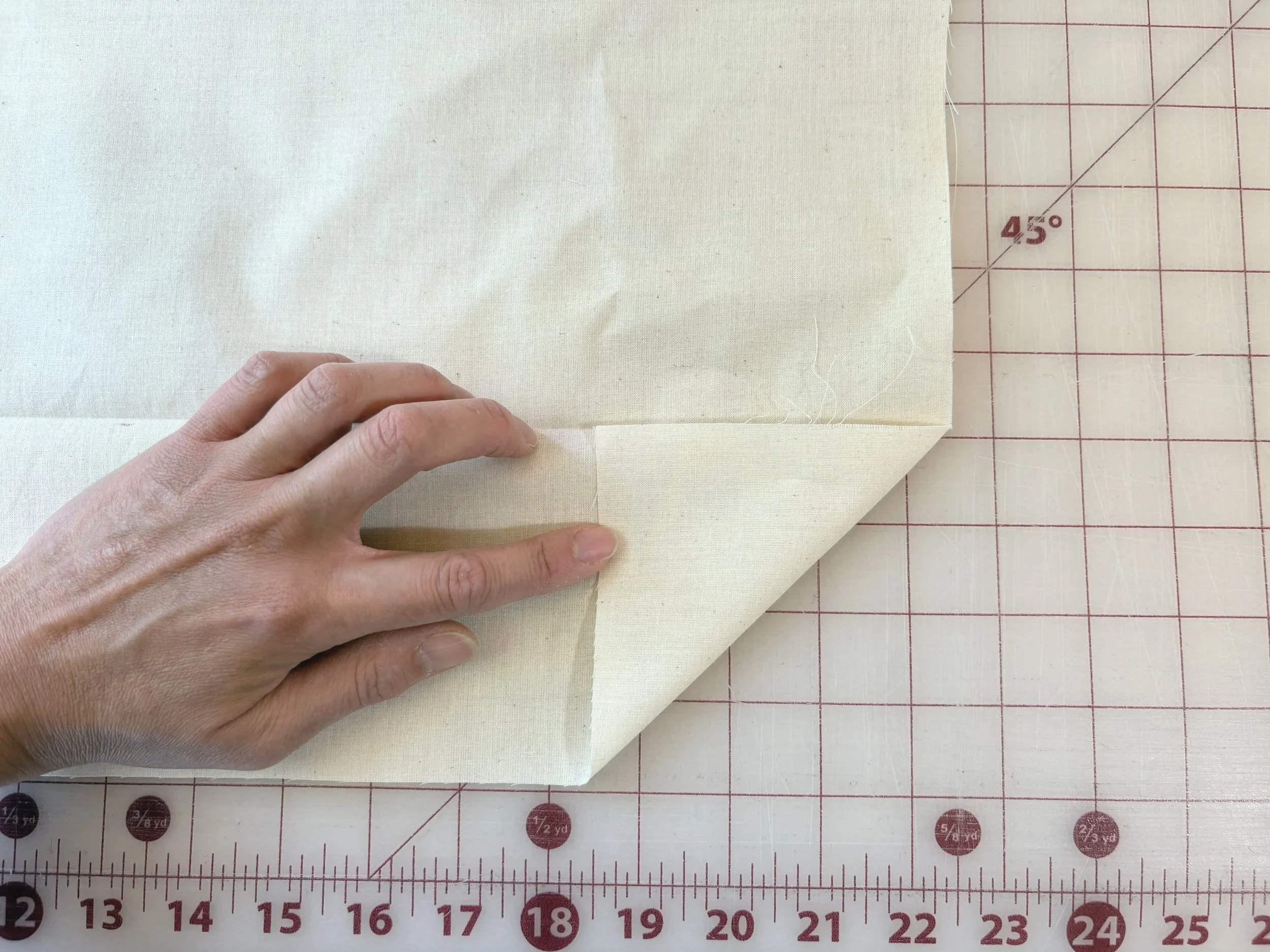 Folding fabric diagonally at a 45-degree angle on a cutting mat to cut a true bias strip