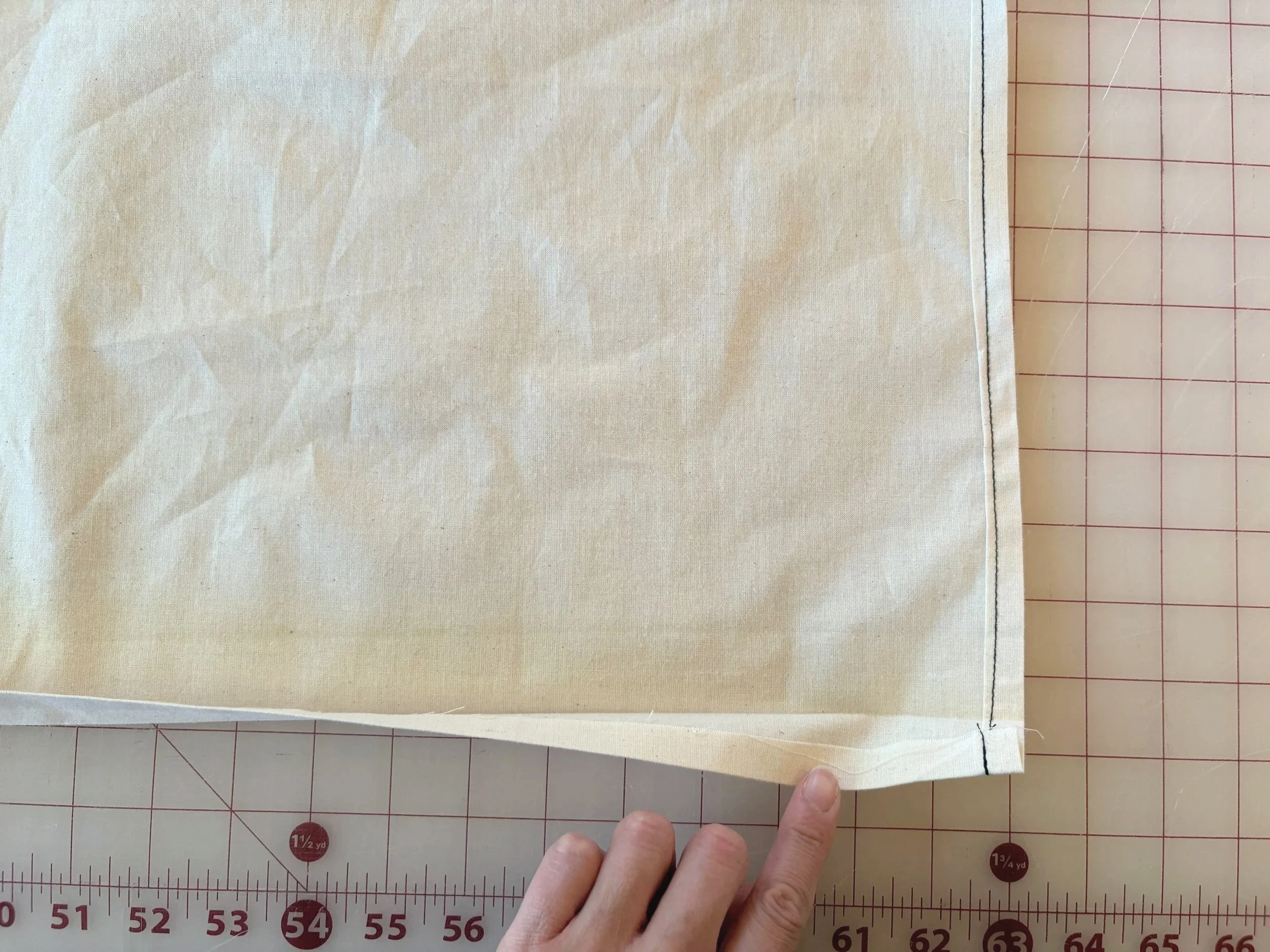 Finished double-fold hem with topstitching, shown at the corner against a measuring grid
