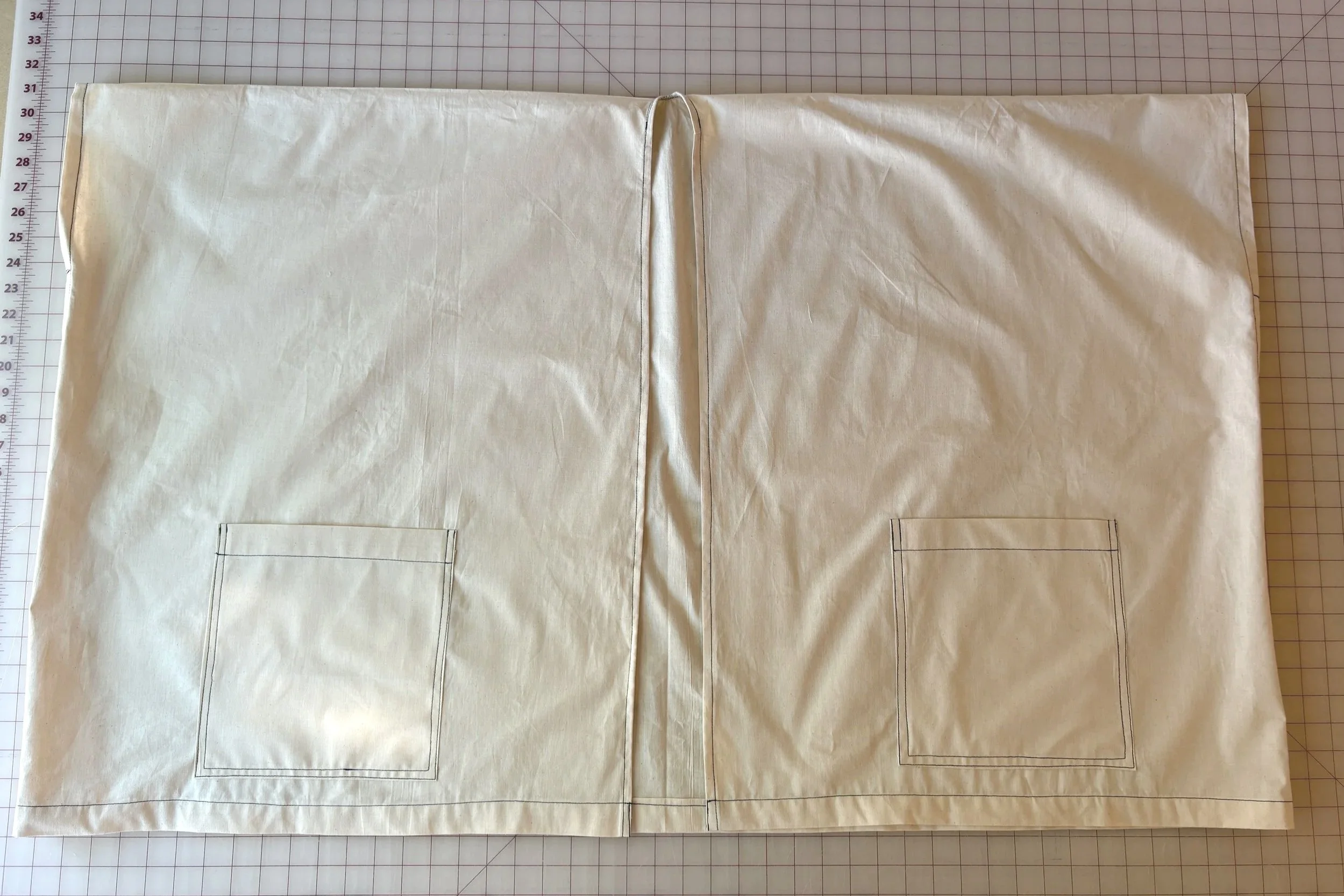 Short wrap laid flat with patch pockets sewn on, placement marked 7 inches from center front and 2 inches from the hem