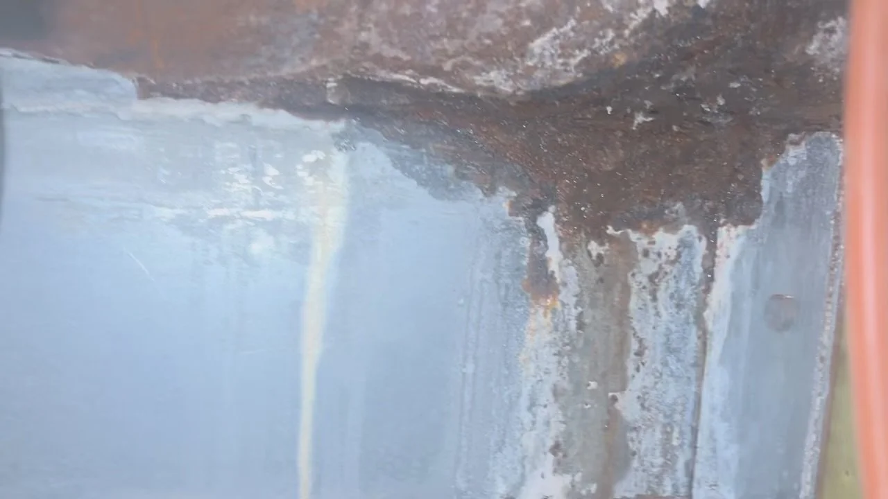 Close-up of corrosion and white deposits on a boiler surface.