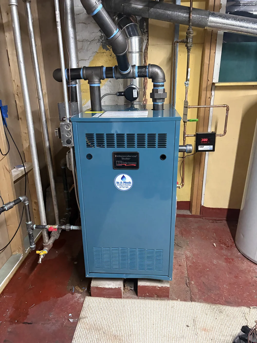 U.S. Boiler Independence steam boiler with connected piping and an In A Flash Heating and Plumbing sticker.