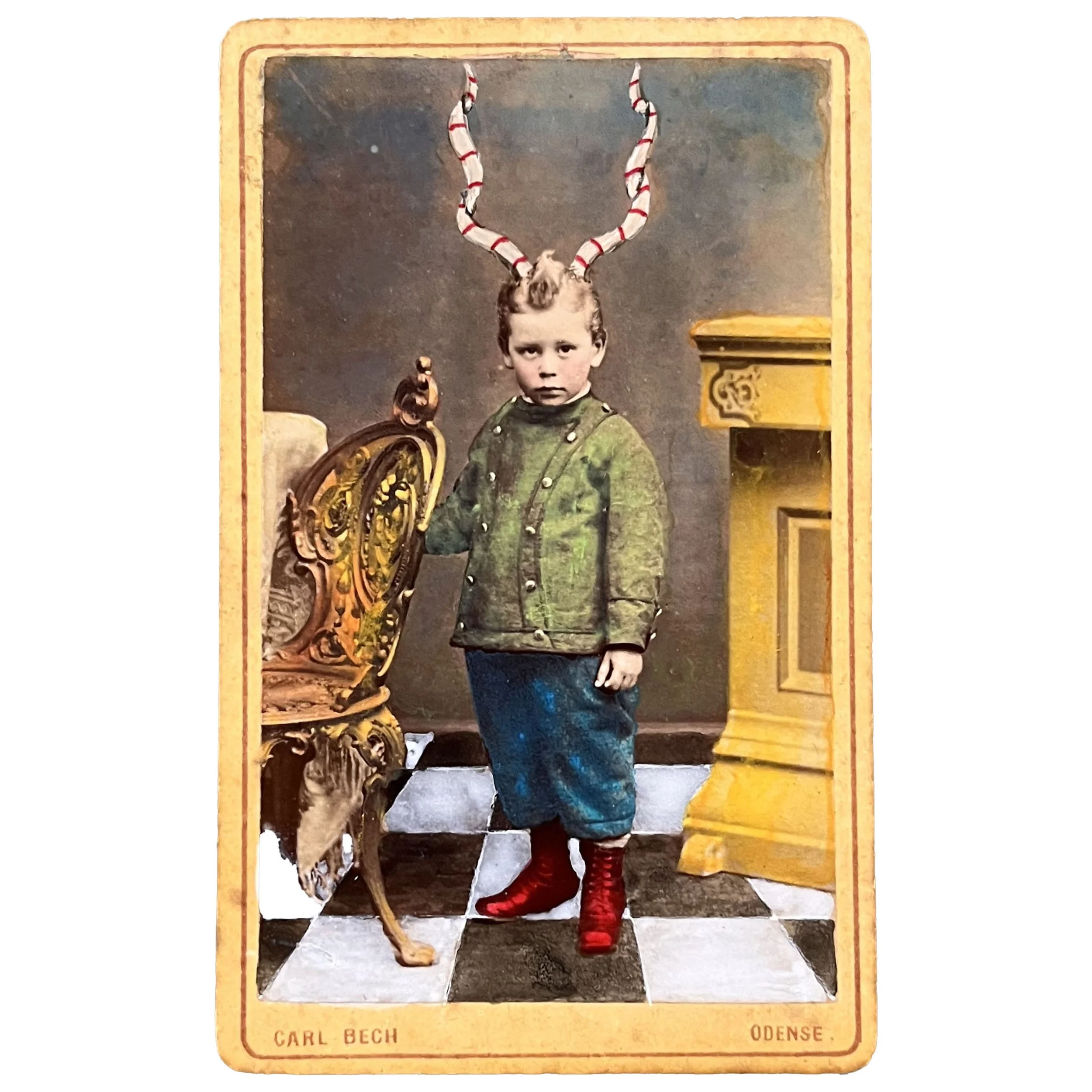 A Victorian photo of a boy in fancy clothes sprouting curly red-striped antlers standing on a black and white checkered floor