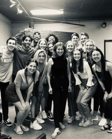 Group of young adults smiling and posing together in a room with black and white filter