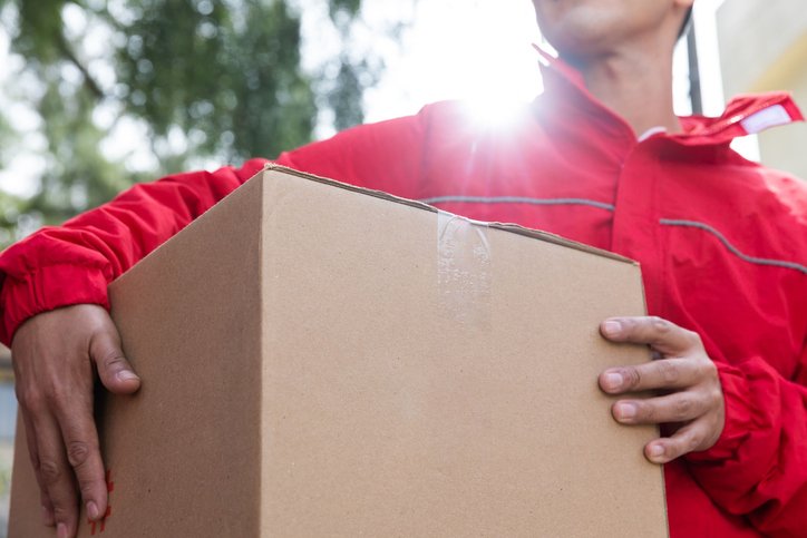 Fragile item courier in a red jacket holding a delicate cardboard box