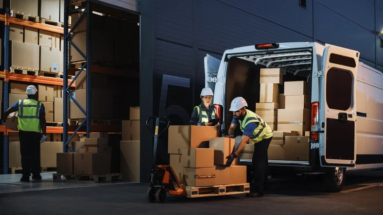 24 hour couriers loading boxes into a van at nighttime