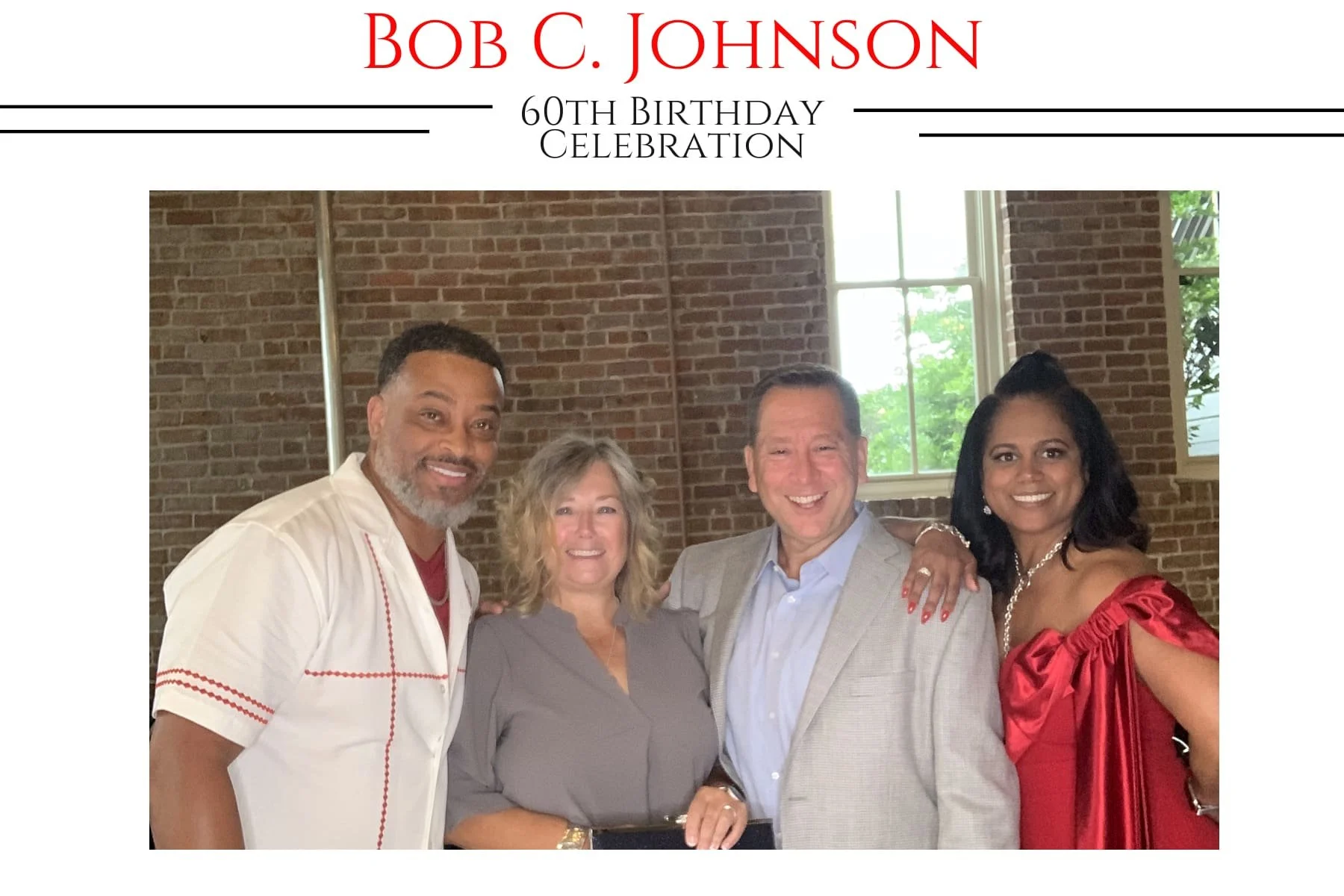 Group of four adults posing together indoors at a birthday celebration, with a brick wall and window in the background. They are smiling and dressed semi-formally, celebrating Bob C. Johnson's 60th birthday.