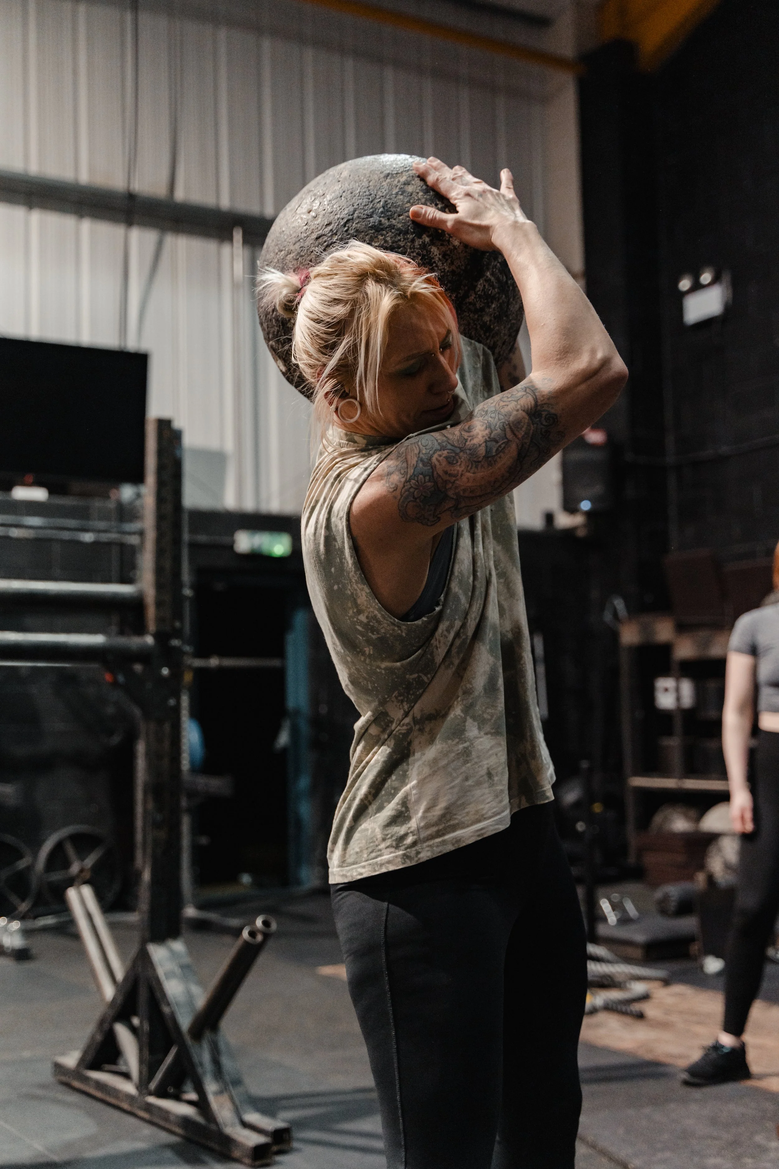 A man ifts a Strongman log above his head during a Strongman class