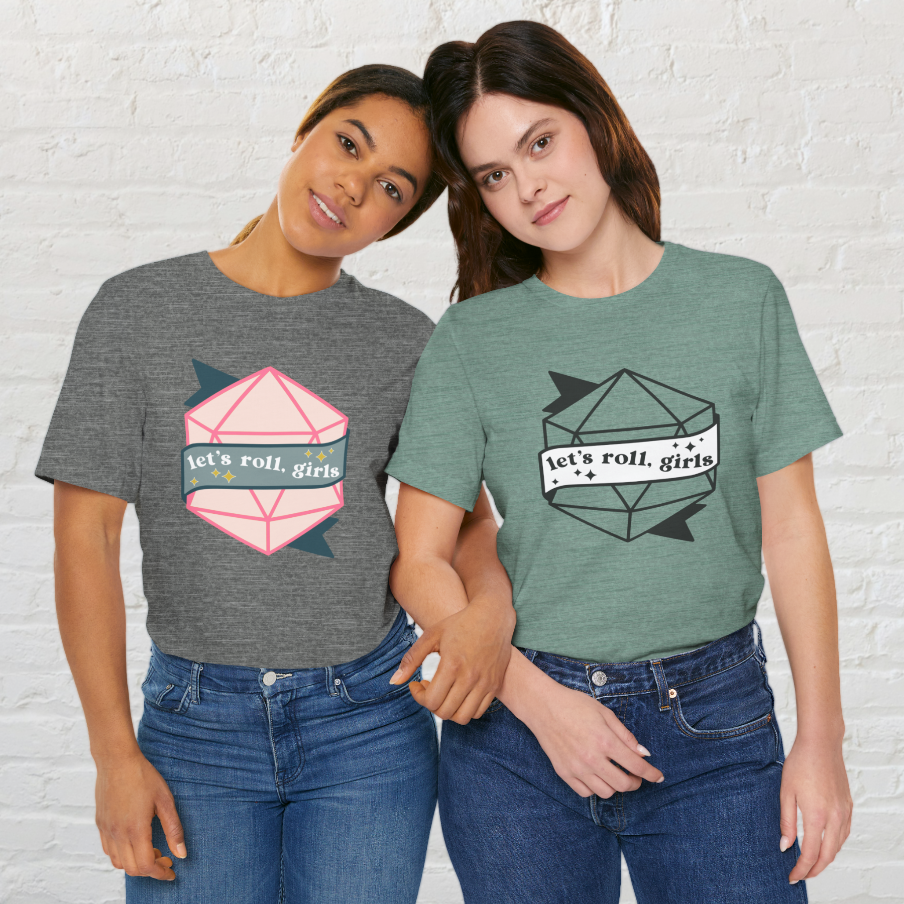 Two women wearing different color versions of the same t-shirt, which says "Let's roll, girls" on a banner in front of a twenty sided die.