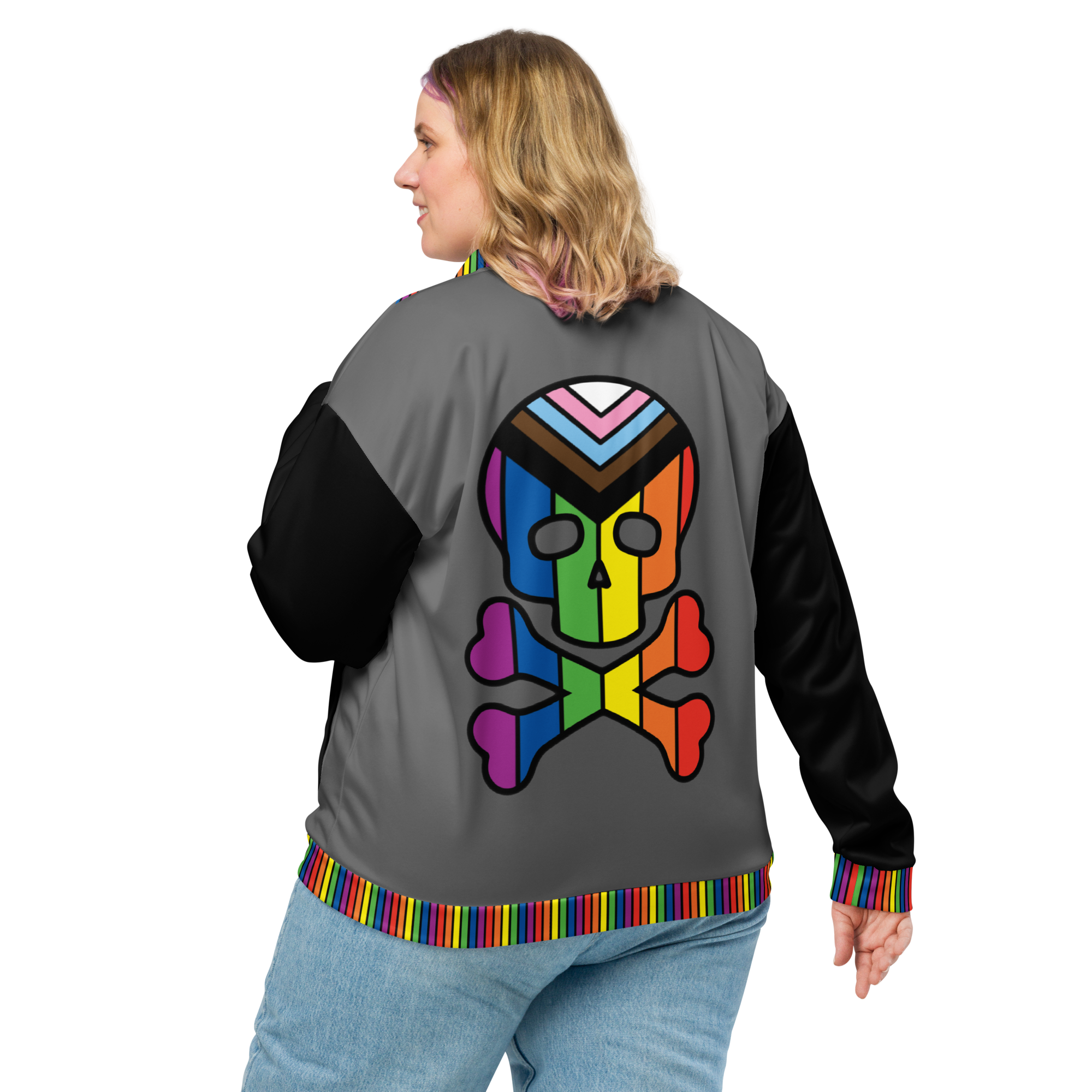 A blonde woman, viewed from behind, wearing a gray bomber jacket with black sleeves and an image of a skull and crossbones with the progress pride flag in it. The sleeves are black, and are trimmed with rainbow stripes.
