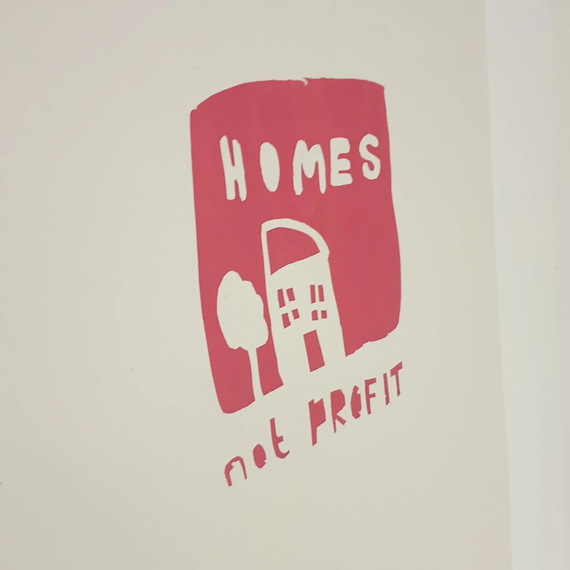 Red stencil reading 'Homes Not Profit', a bold demand from a Food & Solidarity screen-printing session for housing justice.