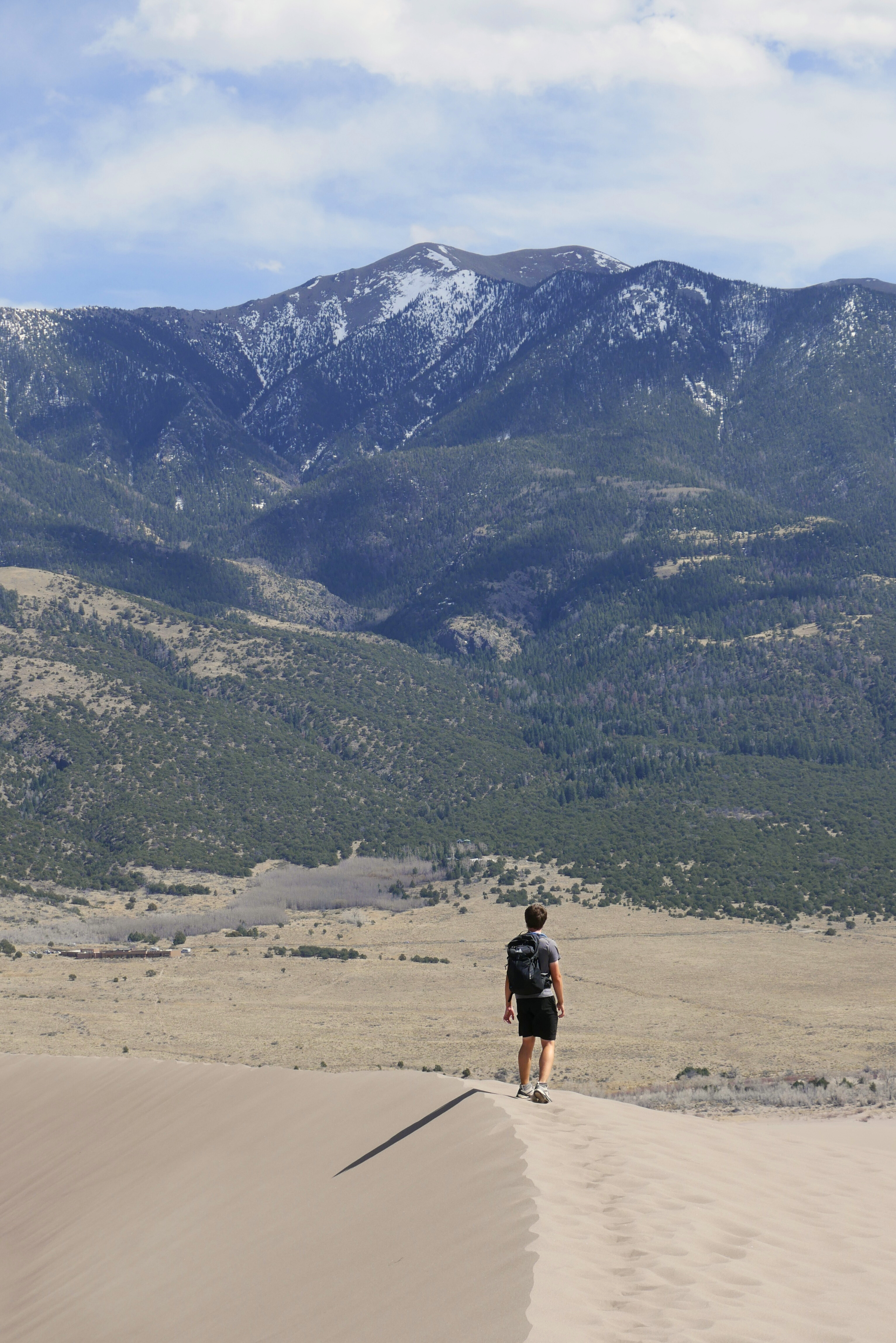 Antoine sur les dunes face à une montagne enneigée