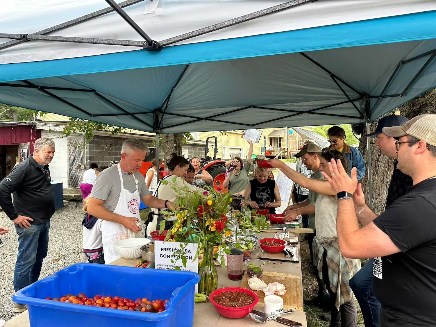Group of people under a ez up tent participating in a salsa making competition