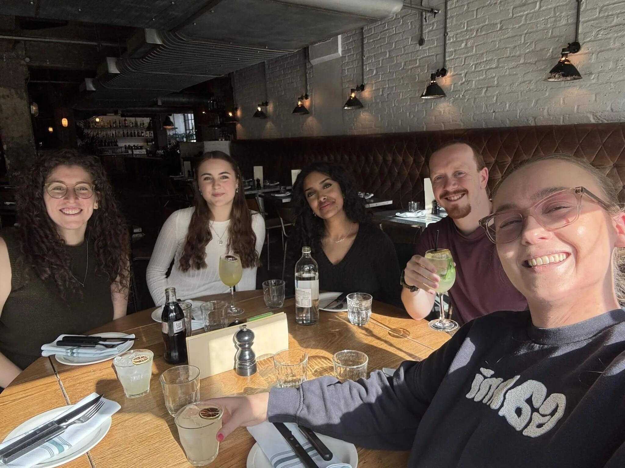 A group of five colleagues including Freya eating pizza at a restaurant on Freya's first day at the new job.