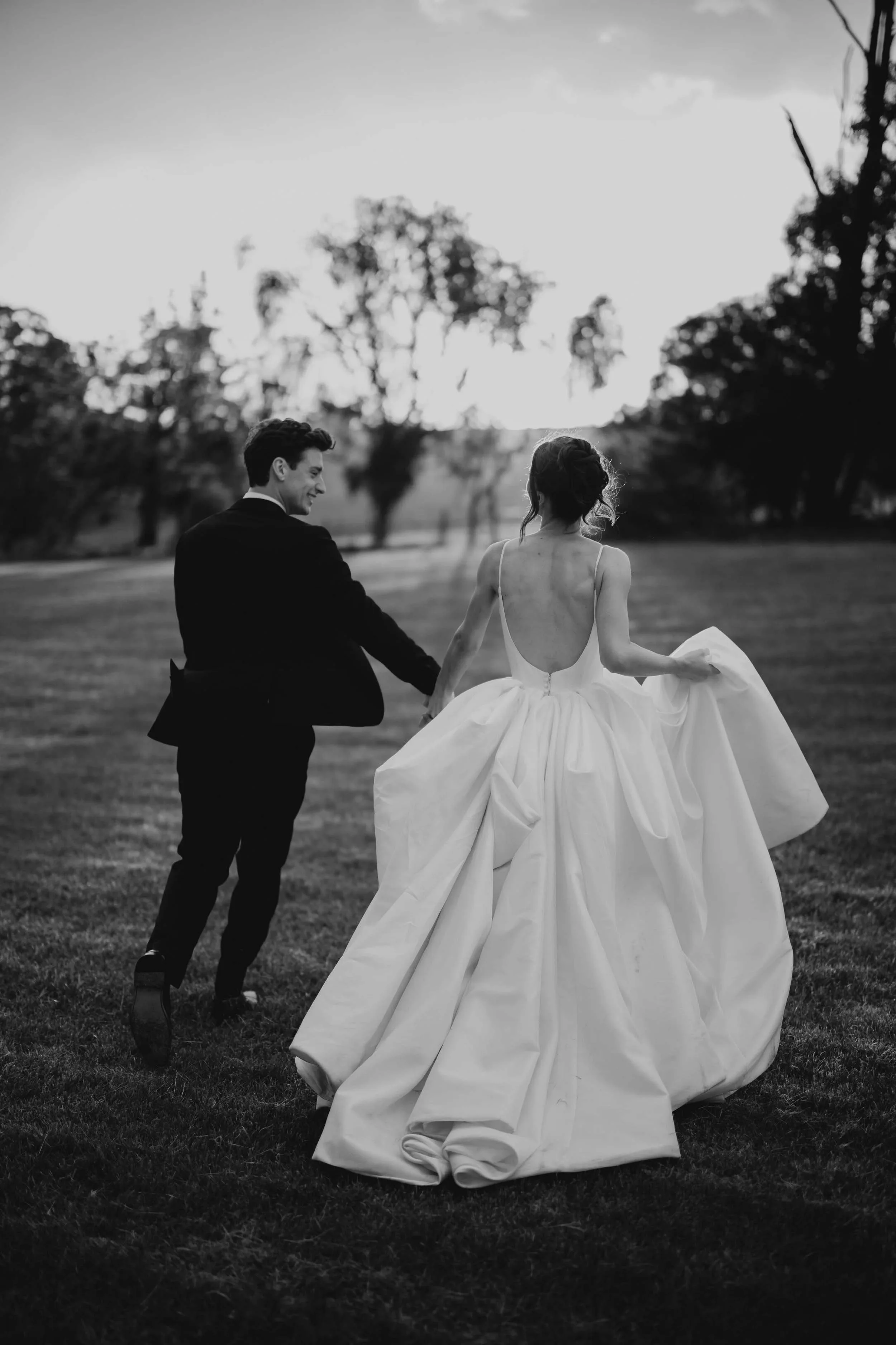 Ruby gathers her ballgown in one hand as she and Jacob run across the lawn at dusk, gum trees dark against the sky.
