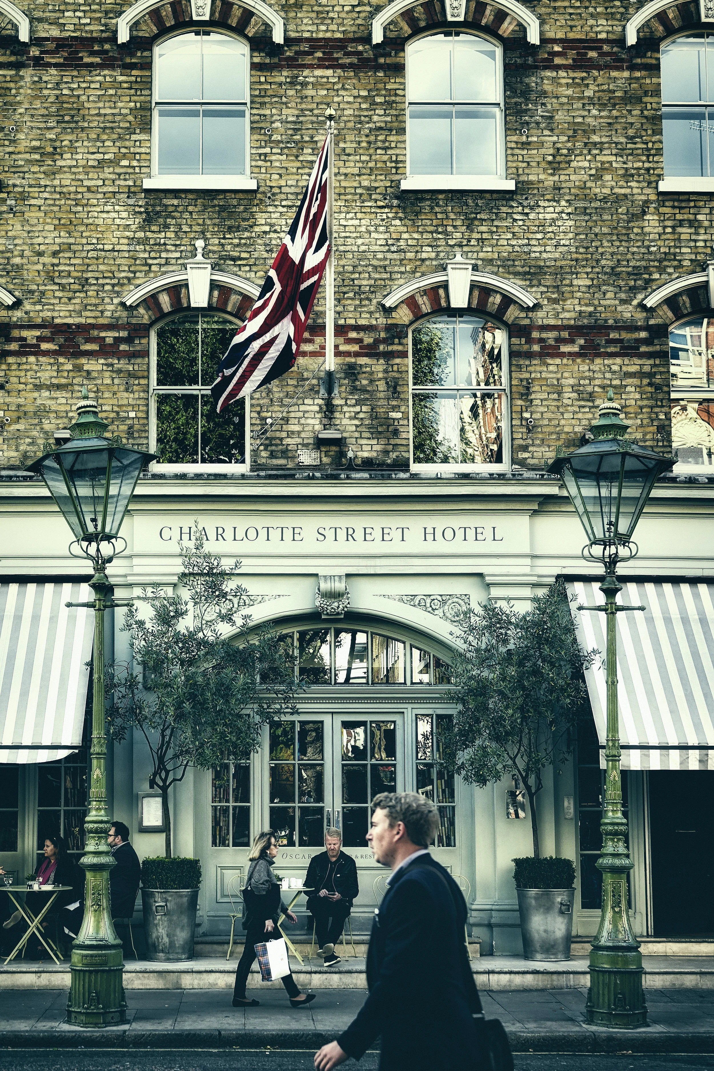 Image shows a business man who has benefited from using AI to book his corporate trip walking in front of a heritage building in a city.