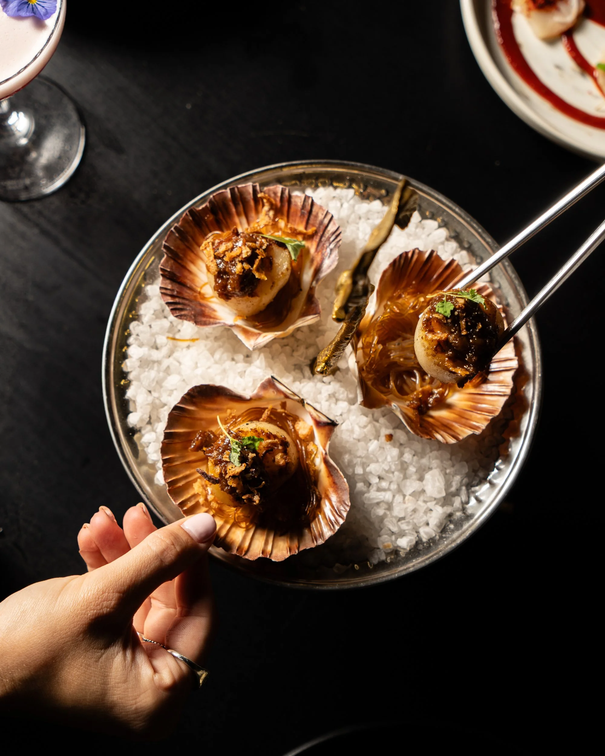 Seafood shells with cooked seafood on ice, garnished with herbs in a glass bowl.