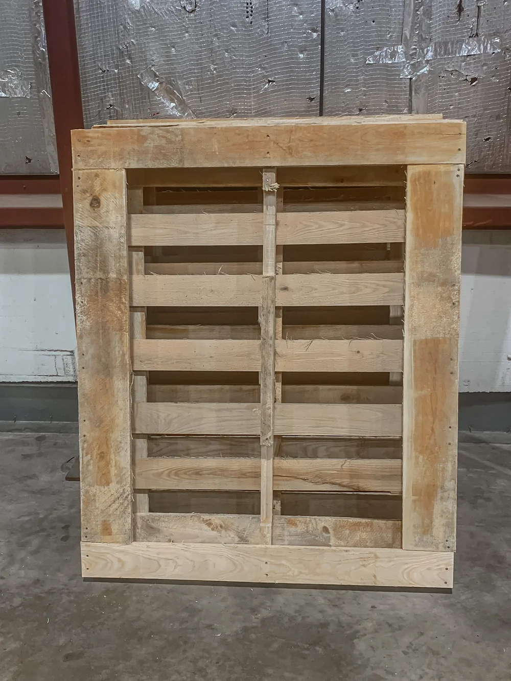 A custom-built wood pallet with a reinforced frame standing in the Rochester Pallets shop