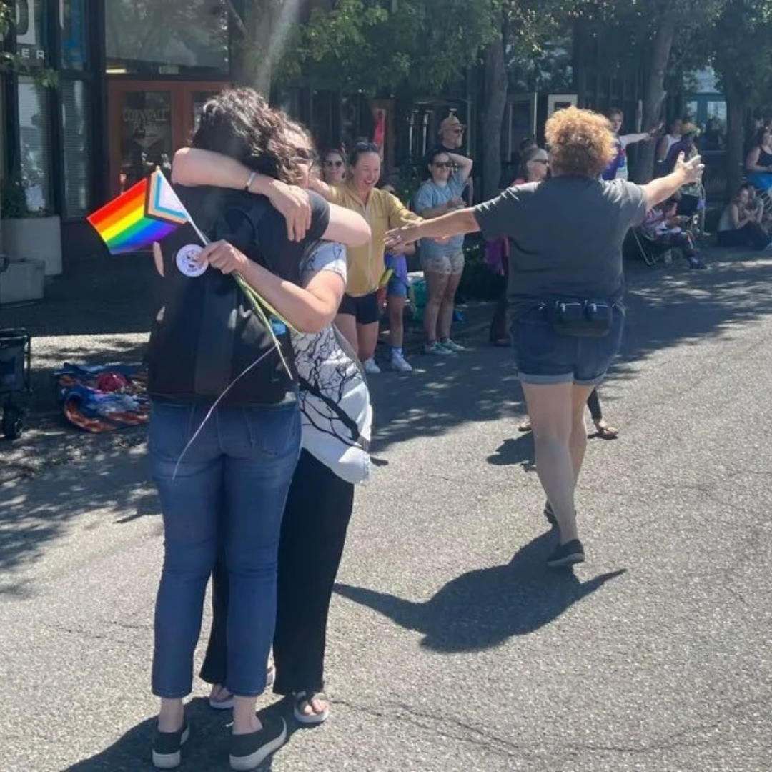 Jill & Michel giving out hugs at a pride parade