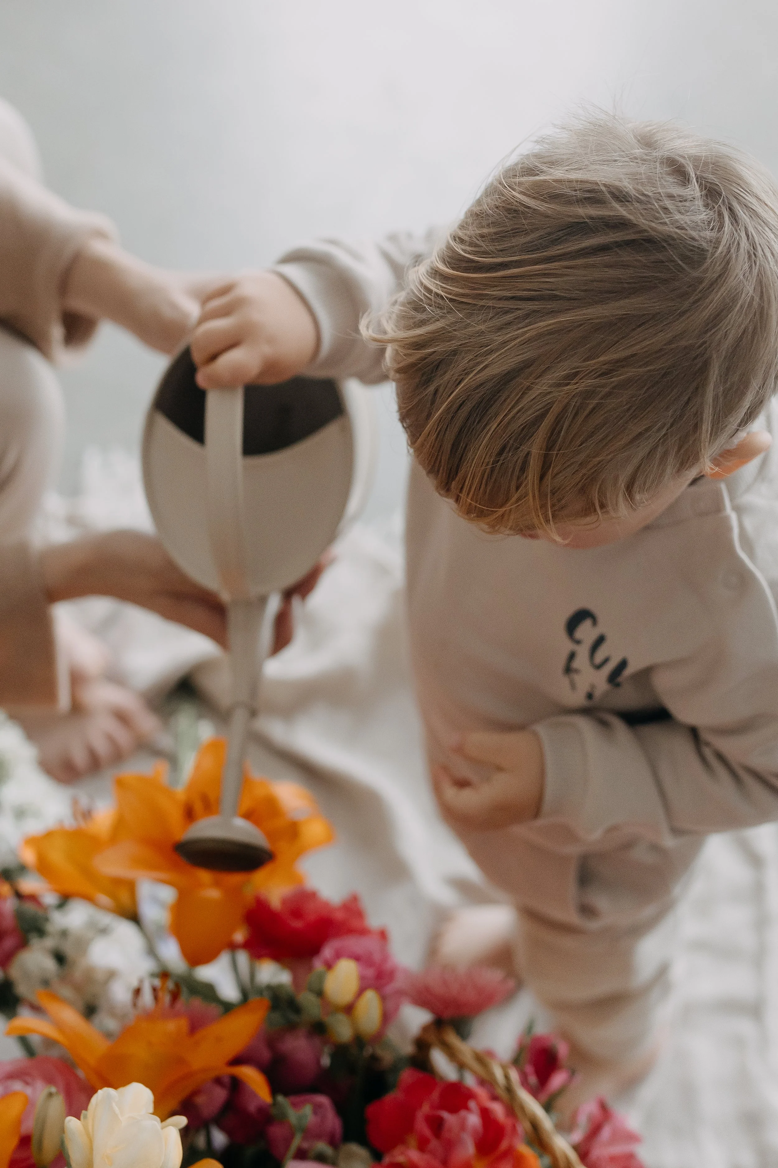 Child arranging colorful flowers on a table, with focus on the child's head and hands.
