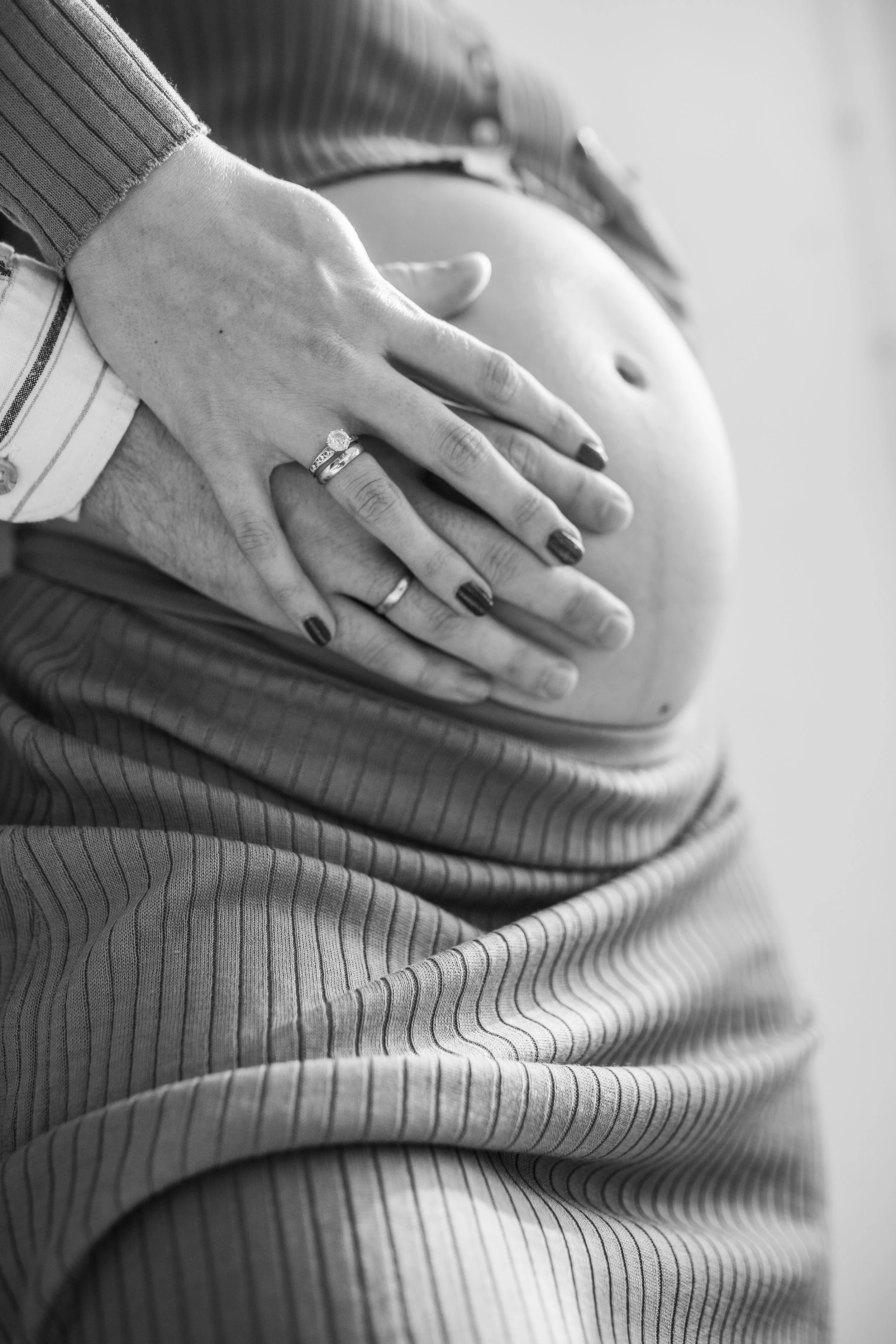 Close-up black and white photo of a hand resting on a pregnant belly.