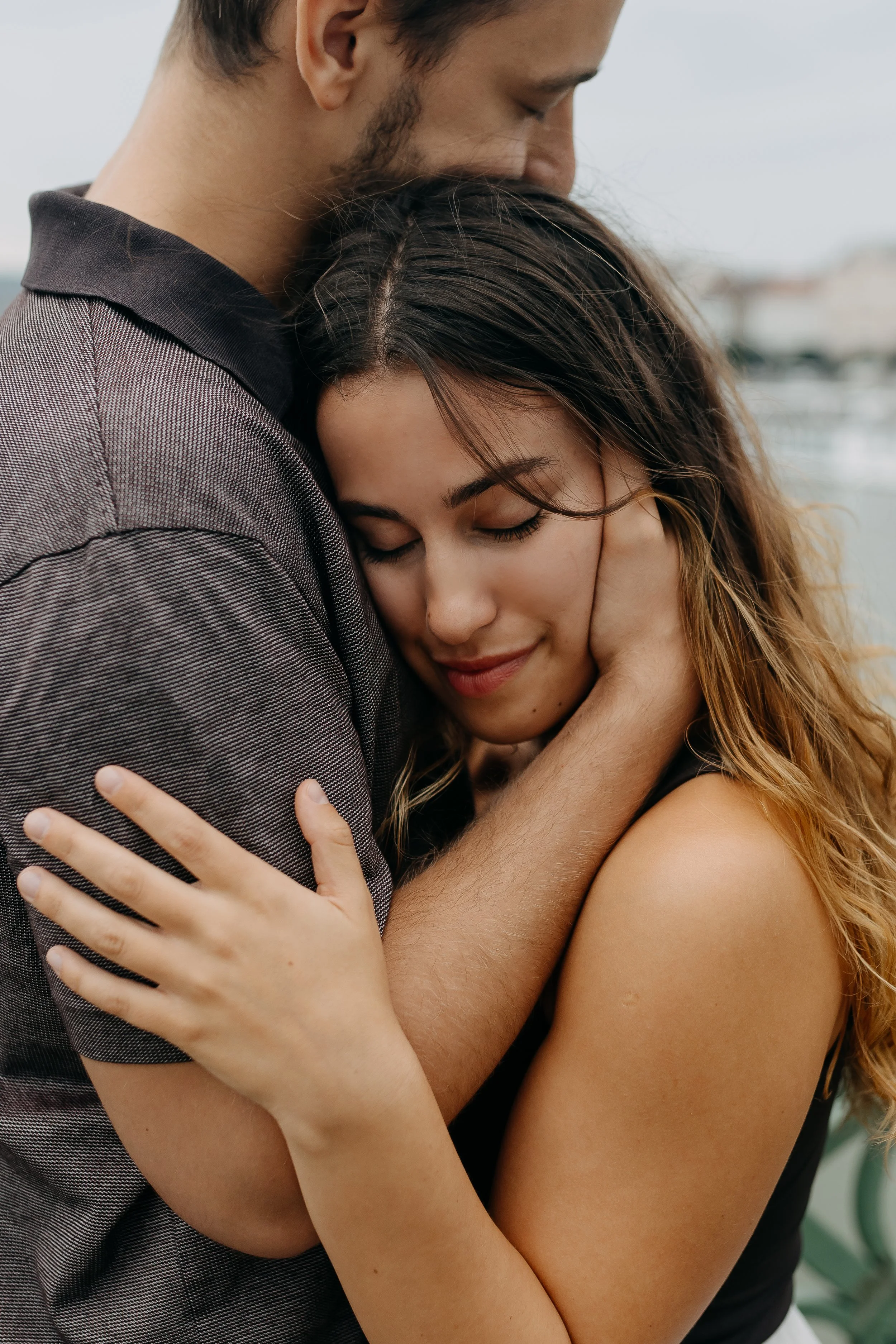 A man and woman embracing each other tightly with their eyes closed, showing affection and comfort.