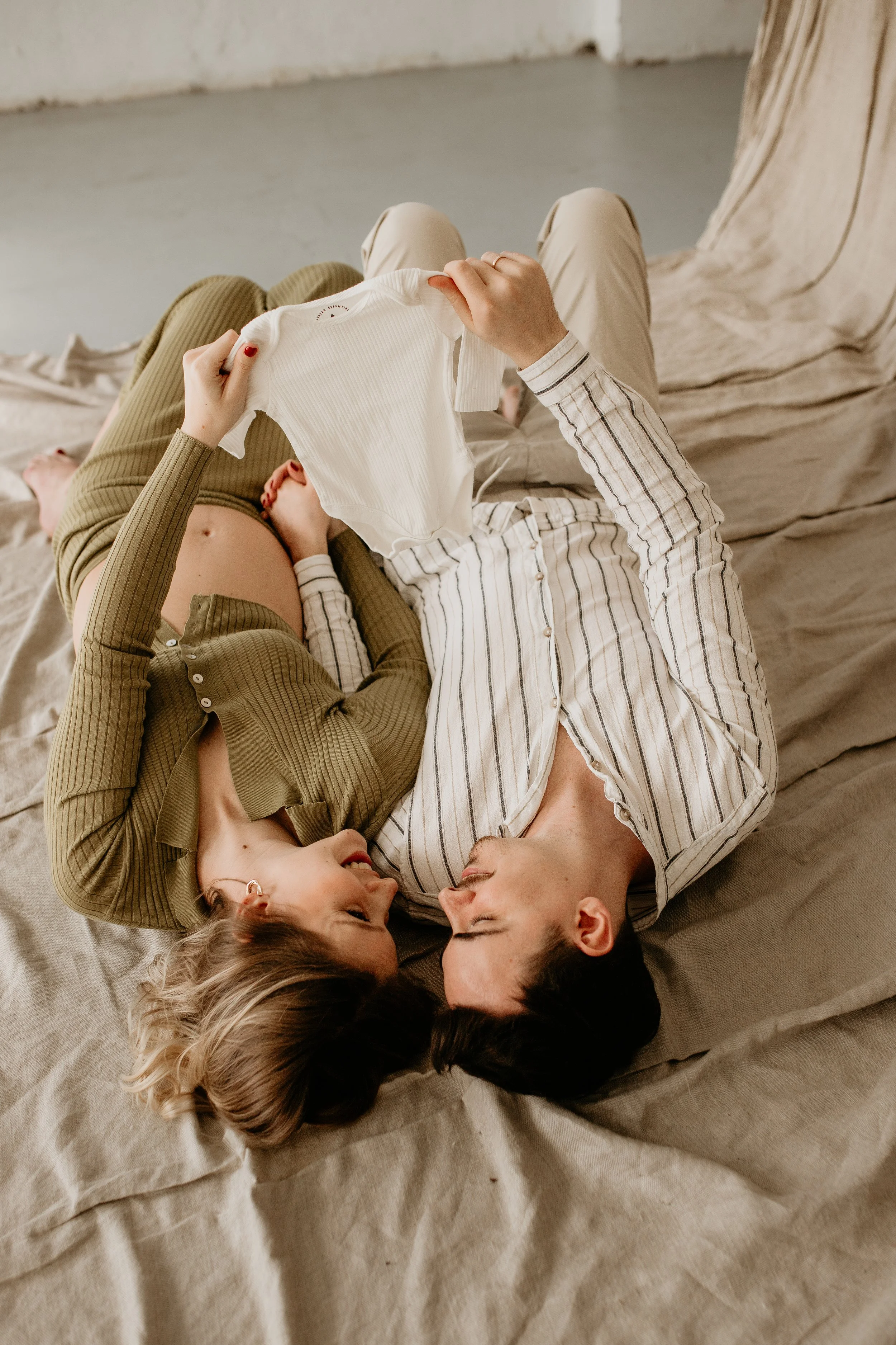 A couple lying on a bed, with two children, enjoying a close moment together.