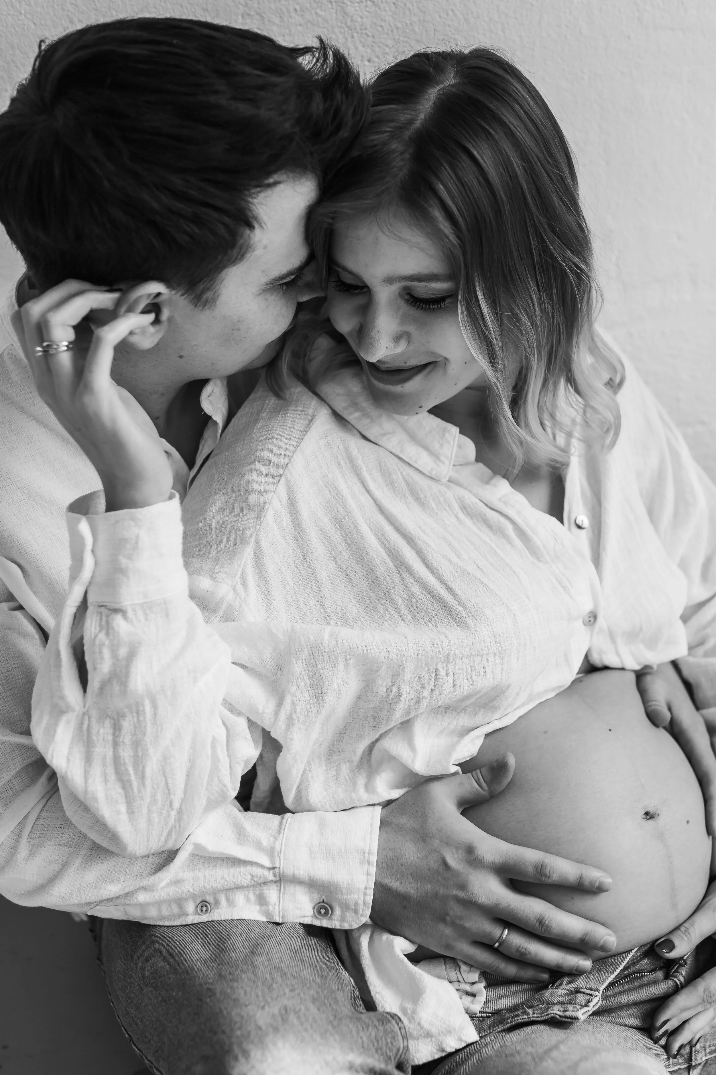Black and white photo of a couple embracing intimately with their foreheads touching, faces close, and eyes closed, conveying affection.