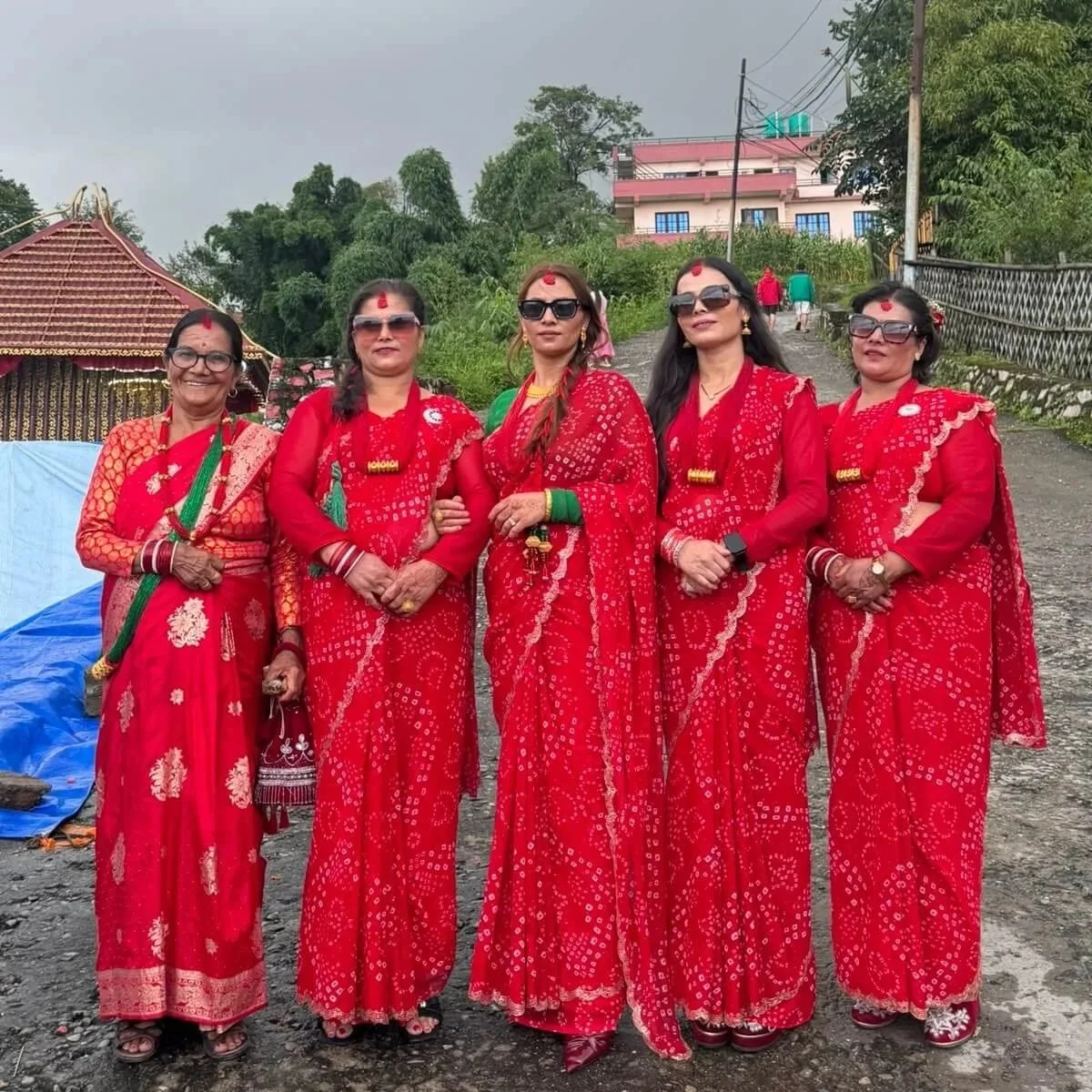 Fünf Frauen in roten Saris und mit traditionellem Schmuck stehen während des Teej-Festes auf einer Straße in Nepal.