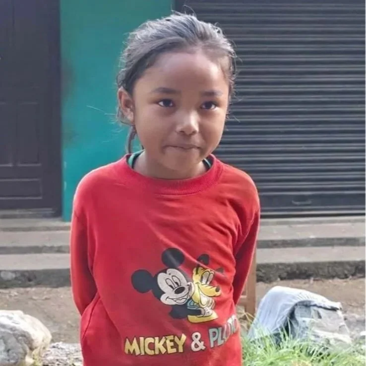 Suna mit rotem Pullover auf dem Schulweg in Nepal