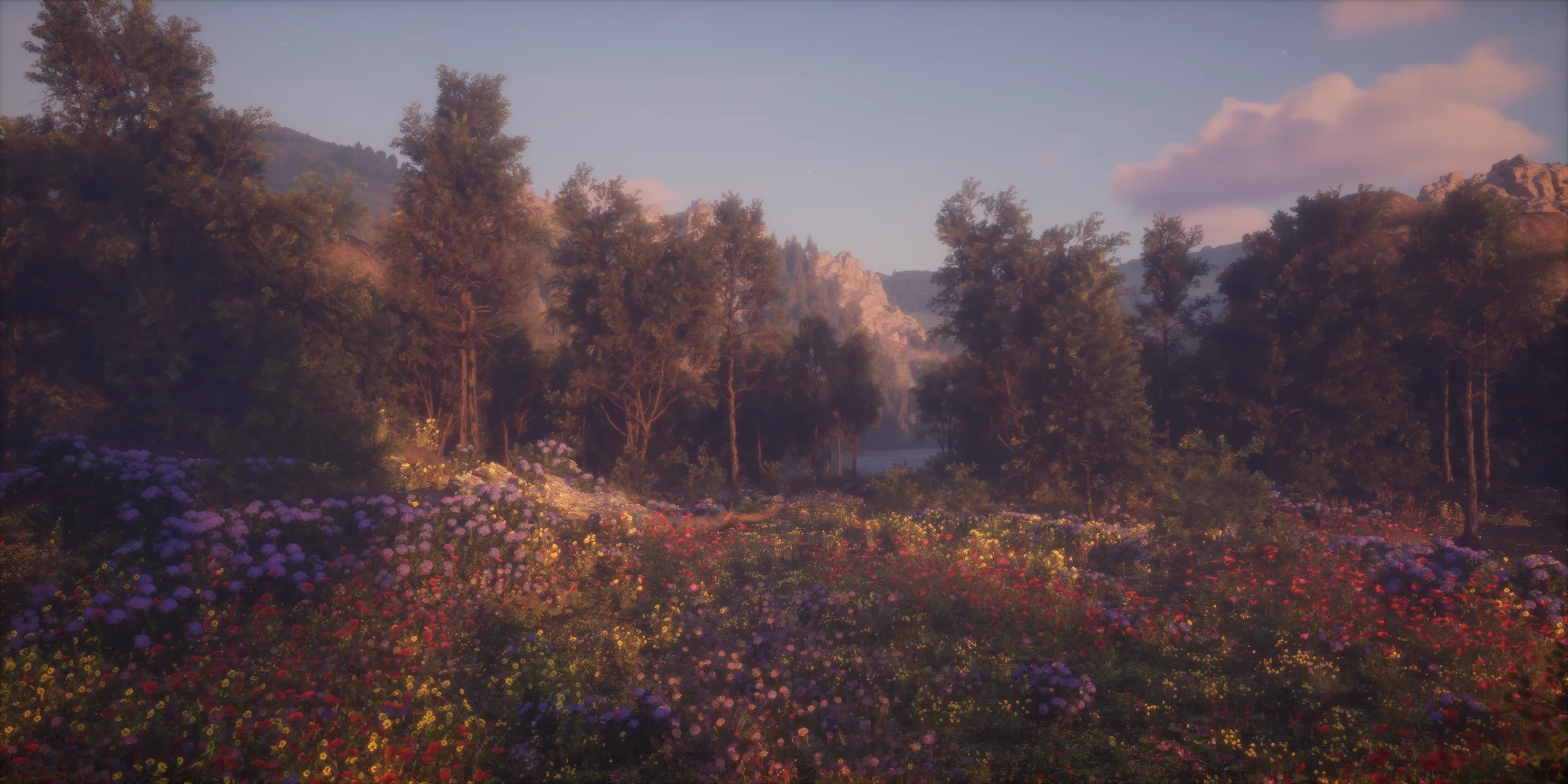 A scenic landscape showing a variety of colorful flowers in the foreground, tall trees in the middle ground, and mountains with a partly cloudy sky in the background during a sunset or sunrise.