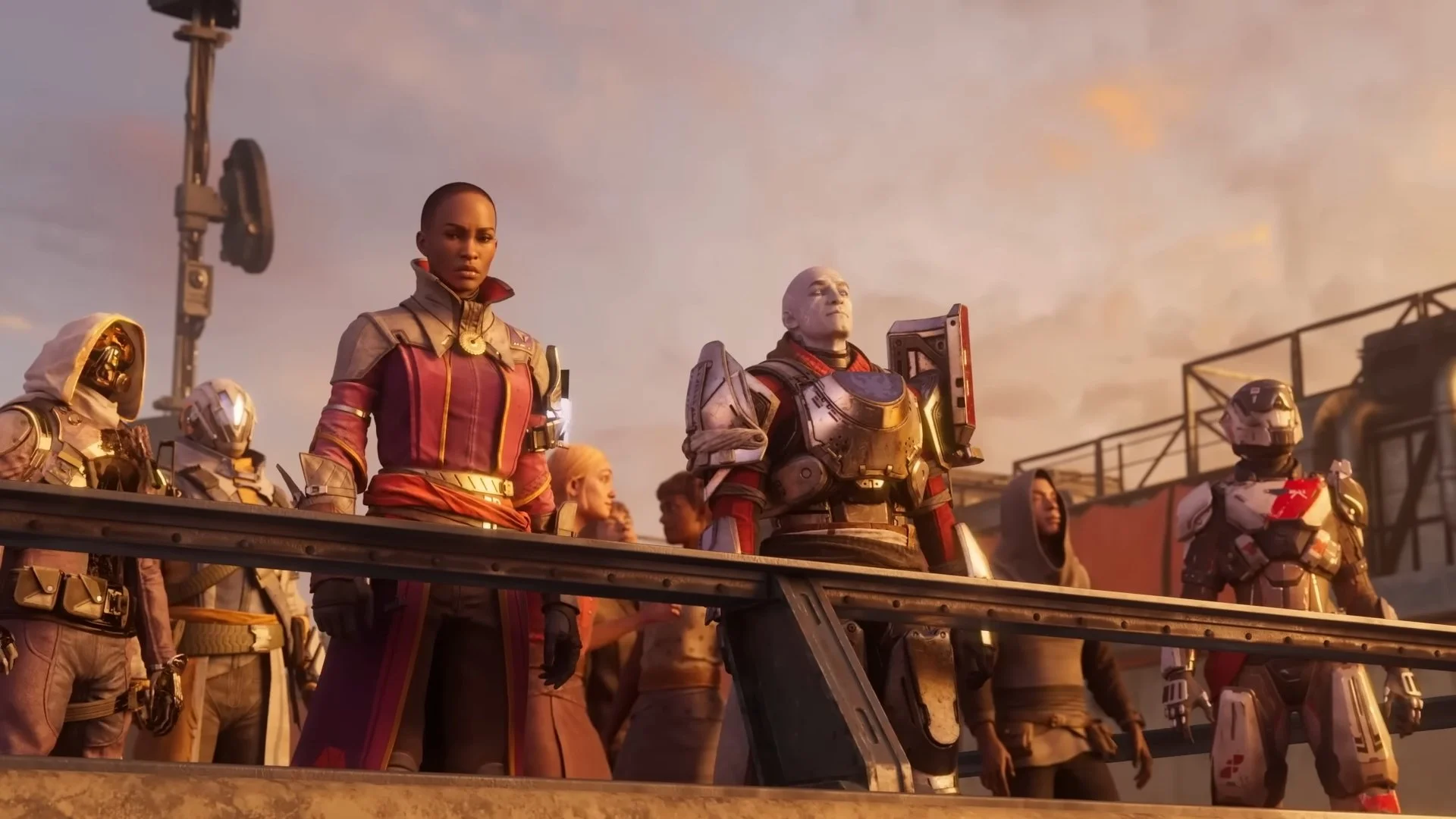 Group of characters in futuristic armor and clothing standing together outdoors during sunset, with a railing and industrial structures in the background.