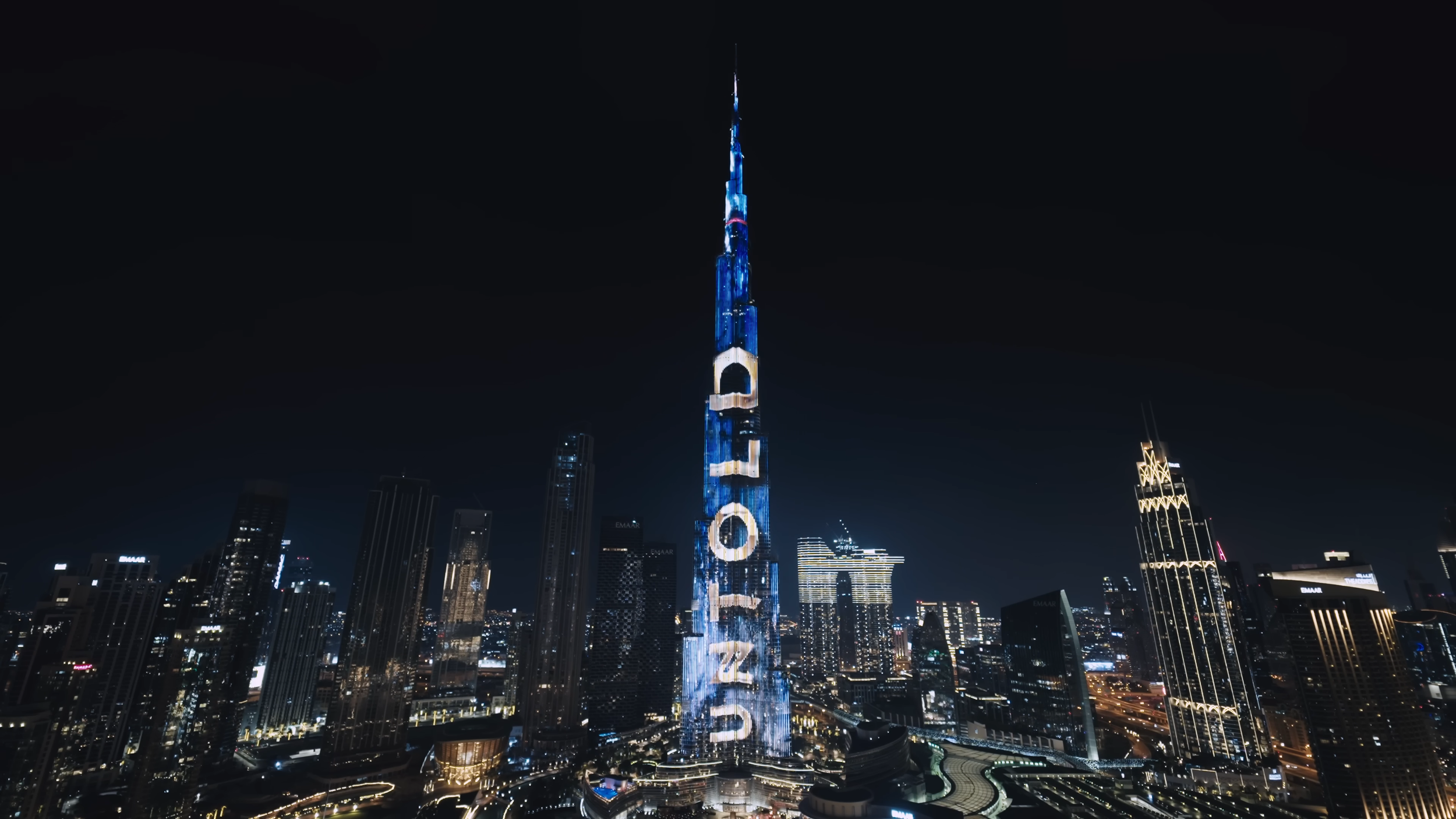 Night view of Dubai skyline with the Burj Khalifa illuminated with blue and purple lights displaying the number 2023.